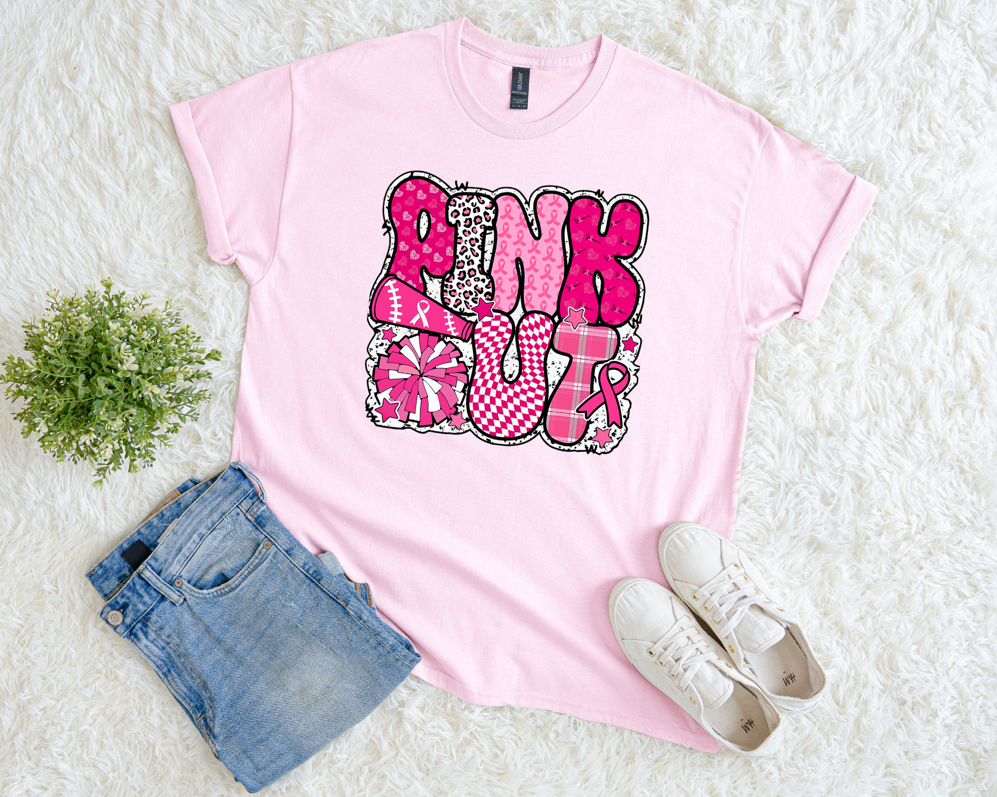 Light pink breast cancer awareness t-shirt with bold patterned lettering that reads “Pink Out” featuring cheer, sports, and pink ribbon designs.