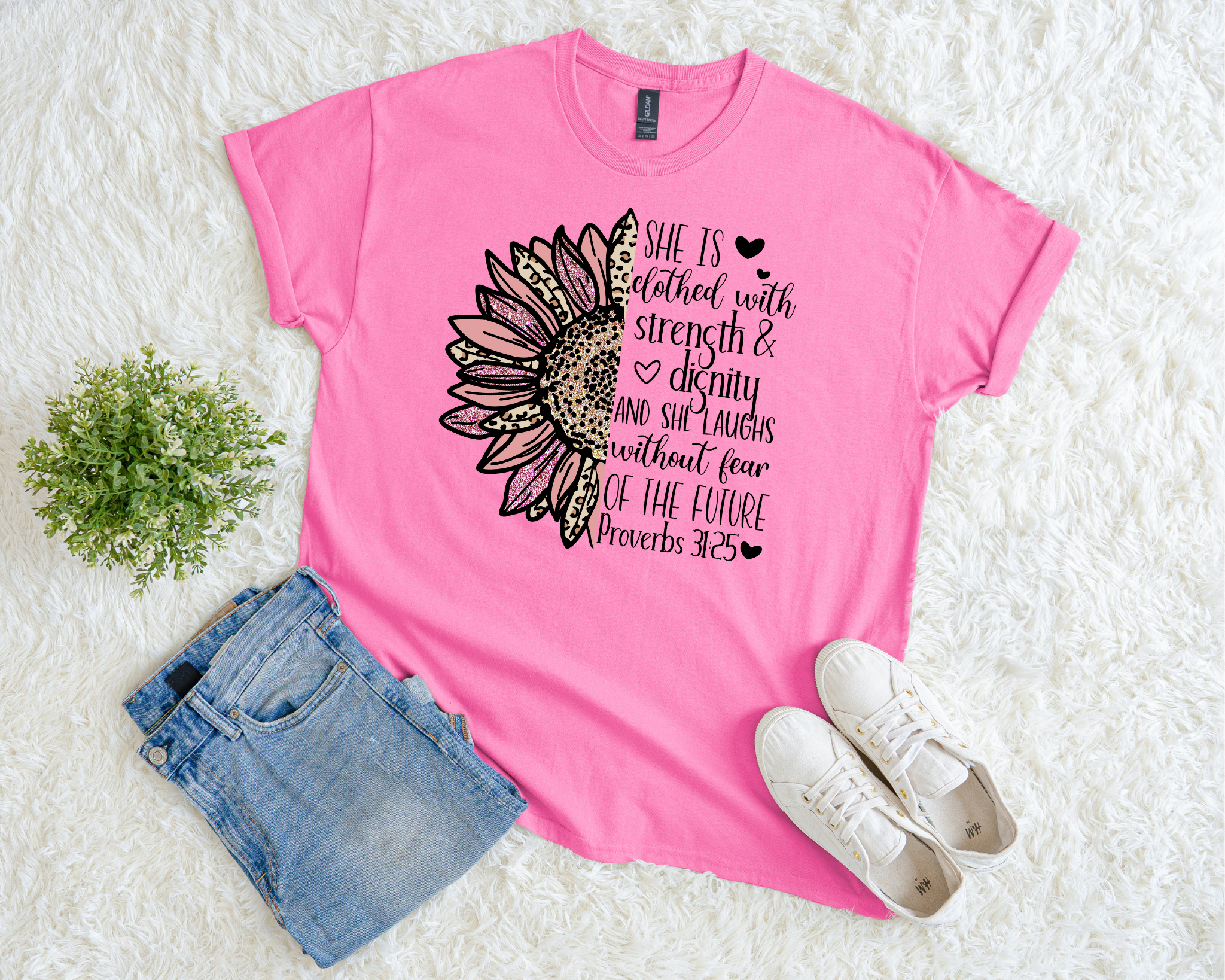 Bright pink Christian t-shirt with a sunflower graphic and Proverbs 31:25 verse reading “She is clothed with strength and dignity, and she laughs without fear of the future.”