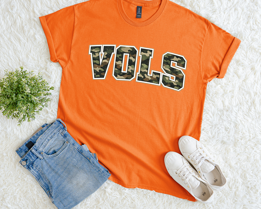 Orange t-shirt with 'VOLS' print, paired with denim shorts and white sneakers on a light background.