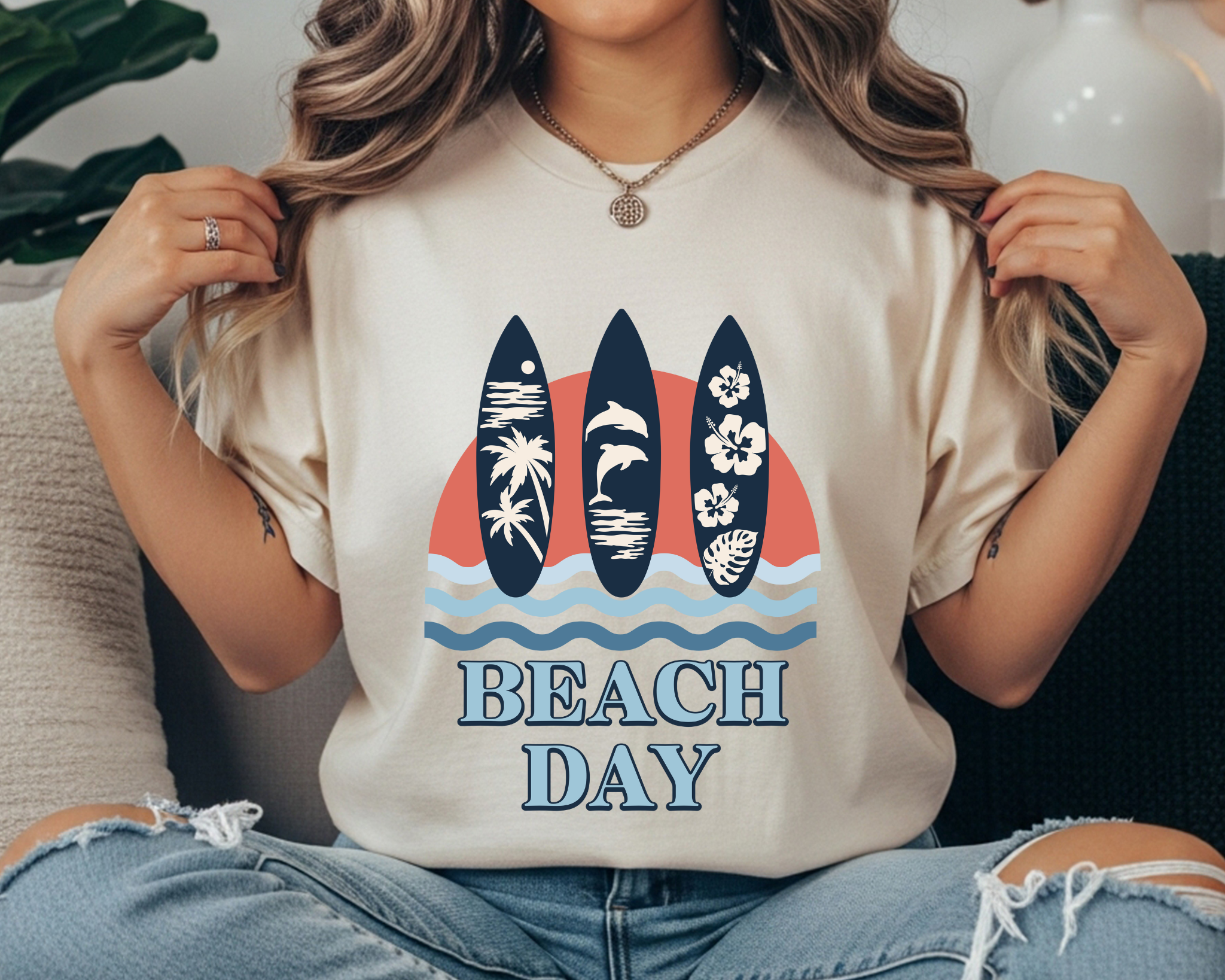 Comfort Colors t-shirt with “Beach Day” text and a coastal graphic of three surfboards over ocean waves and a coral sunset in navy and light blue.