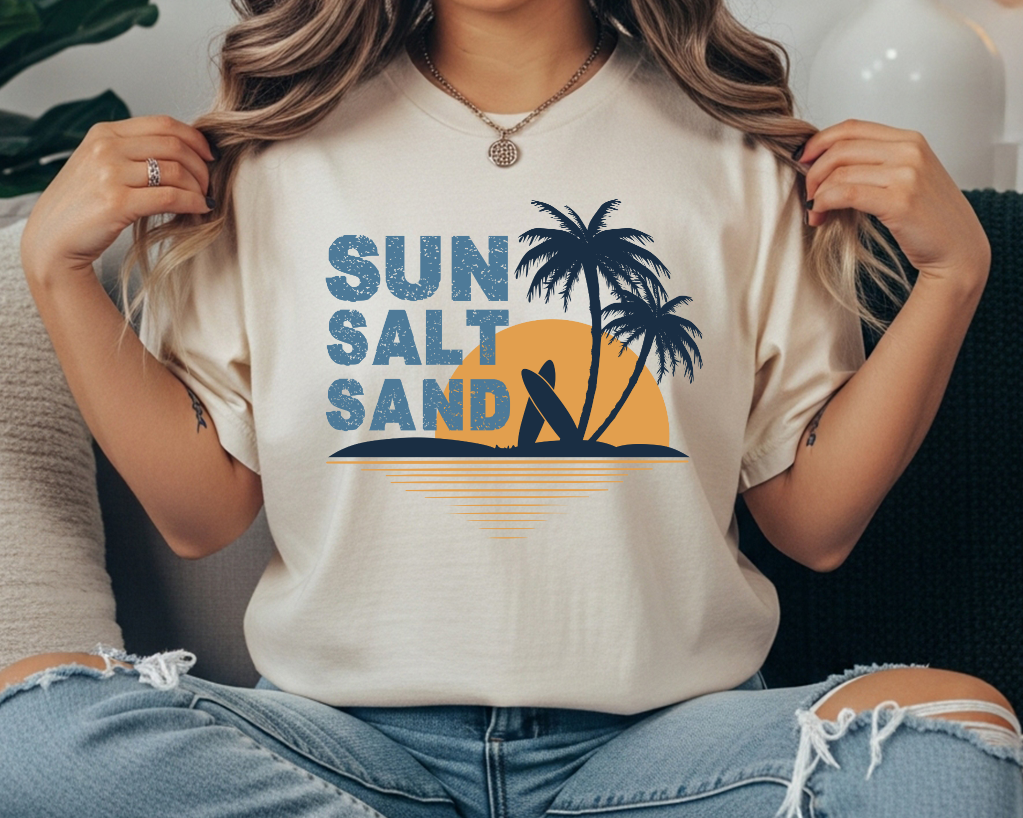 Comfort Colors t-shirt with “SUN SALT SAND” text and a palm tree sunset graphic in blue and golden yellow.