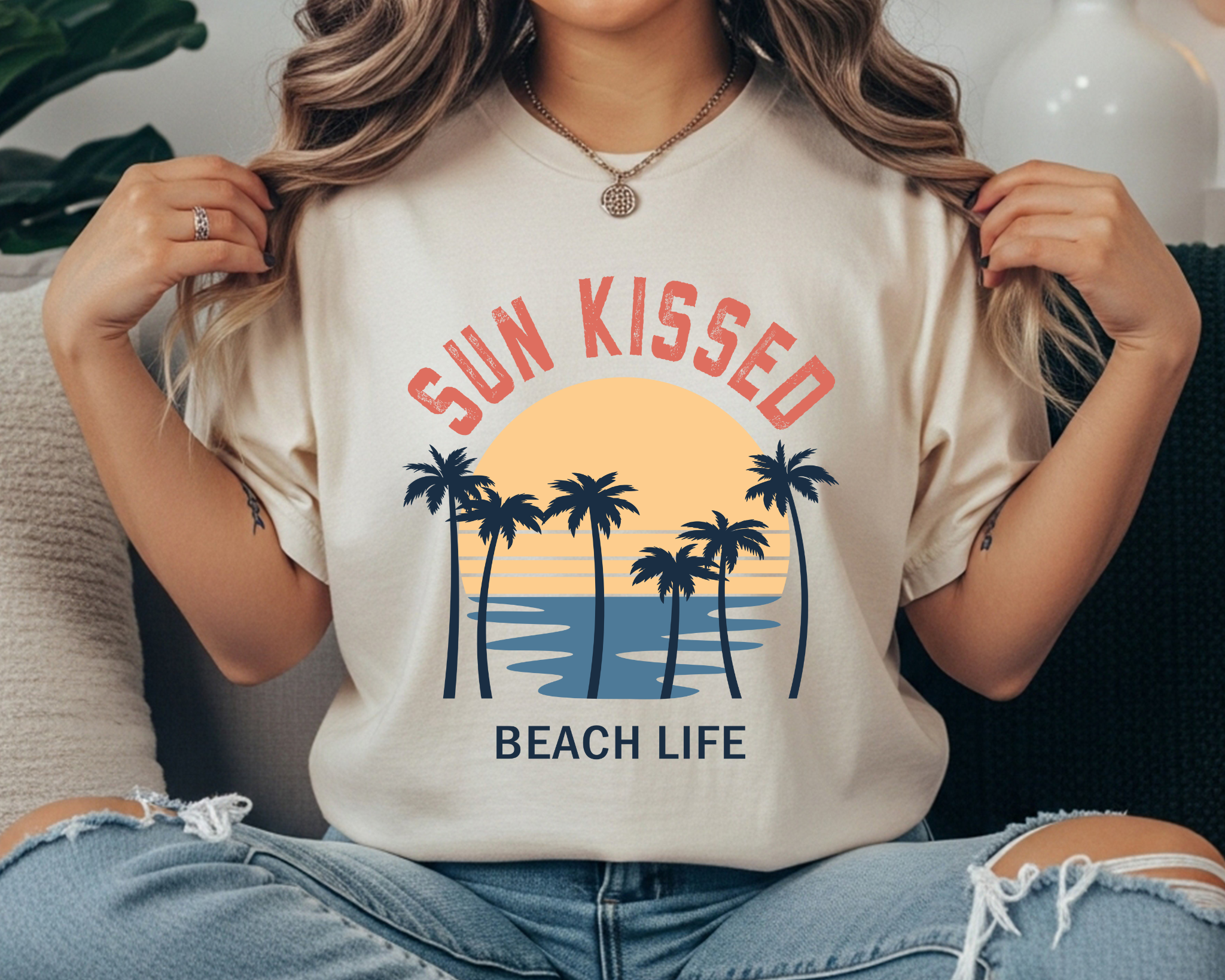 Comfort Colors t-shirt with “Sun Kissed” and “Beach Life” text and a retro palm tree sunset ocean graphic in navy, coral, and golden yellow.