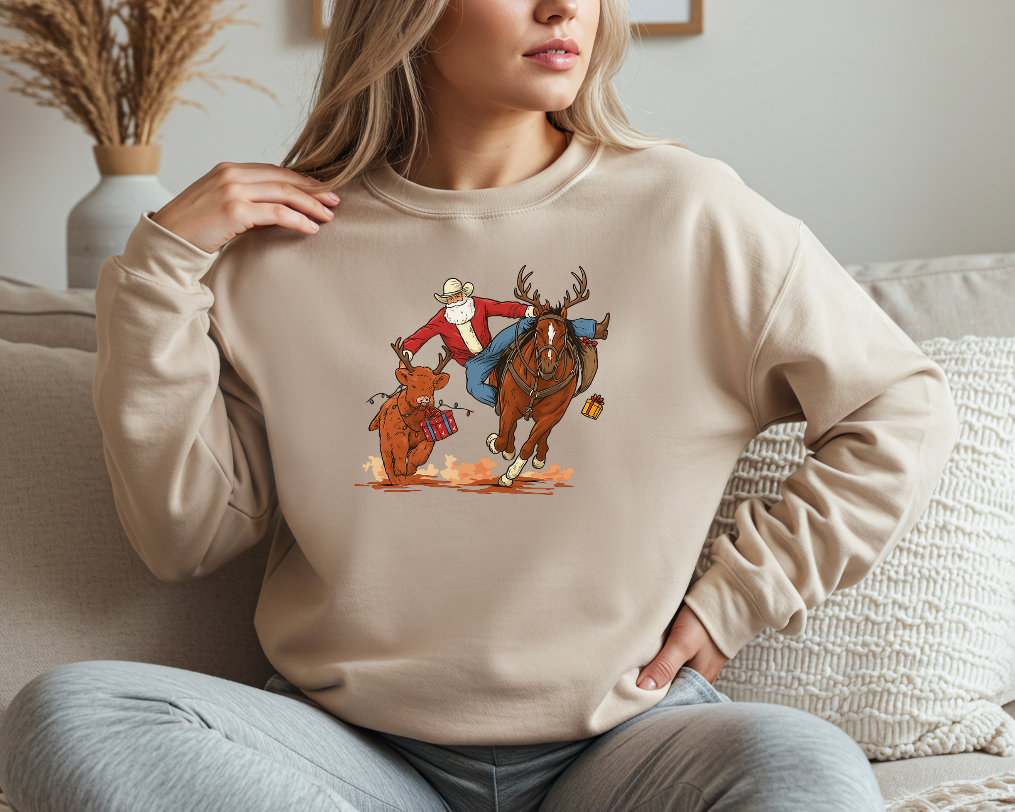 Cowboy Santa sweatshirt featuring Santa roping a reindeer, sitting on a couch in a cozy holiday setting.