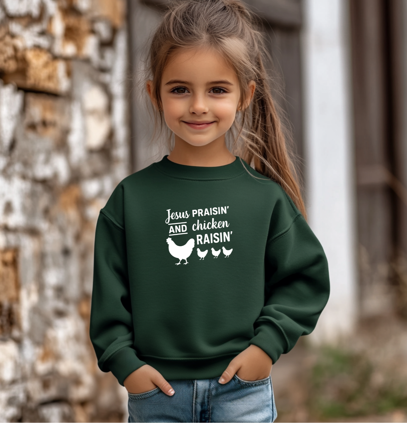 Child wearing a green sweatshirt with text and chicken illustrations outdoors.