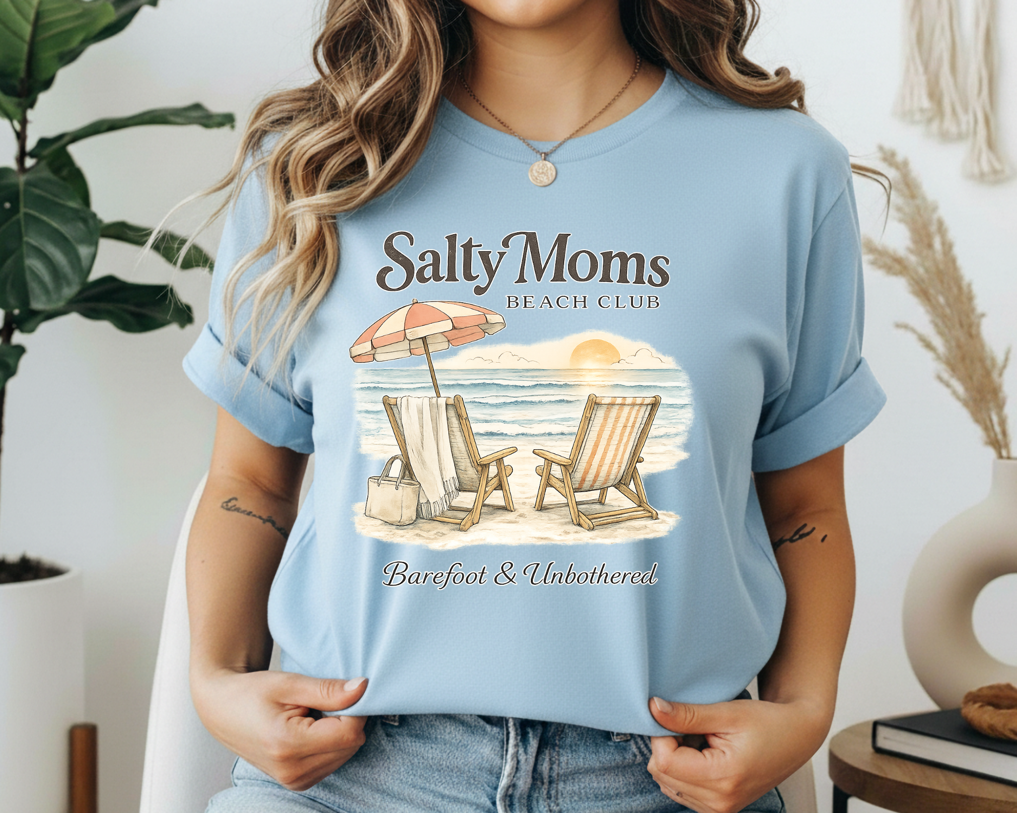 Person wearing a light blue t-shirt with a beach graphic and text.