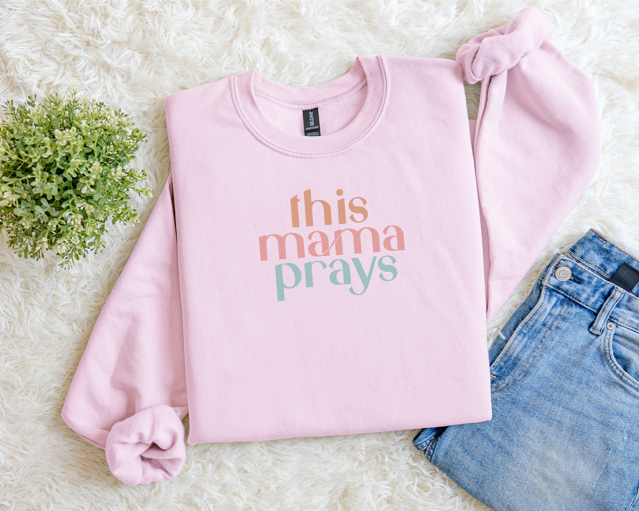Light pink Christian sweatshirt with multicolor text reading “This Mama Prays.