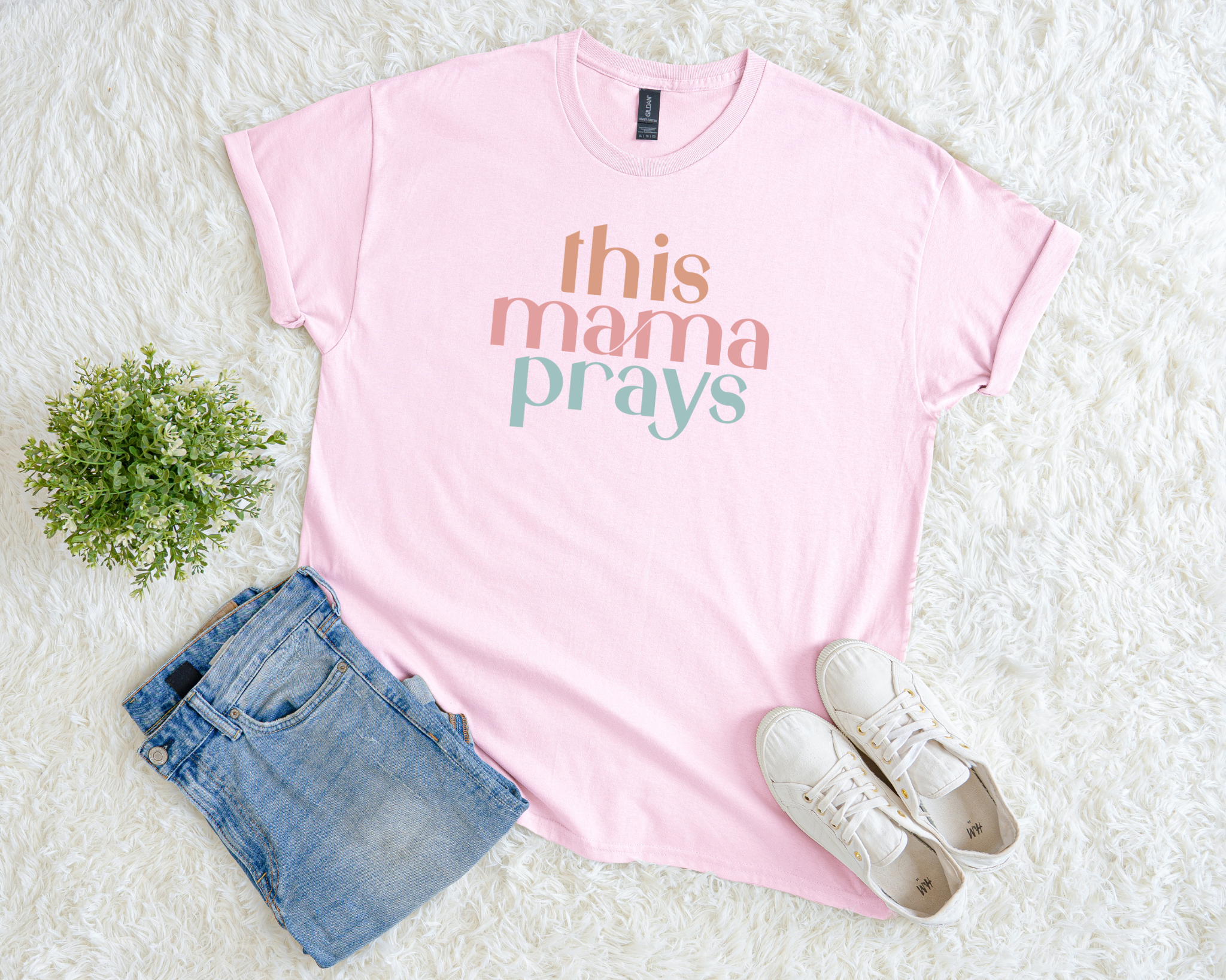 Light pink Christian t-shirt with multicolor text reading “This Mama Prays.”