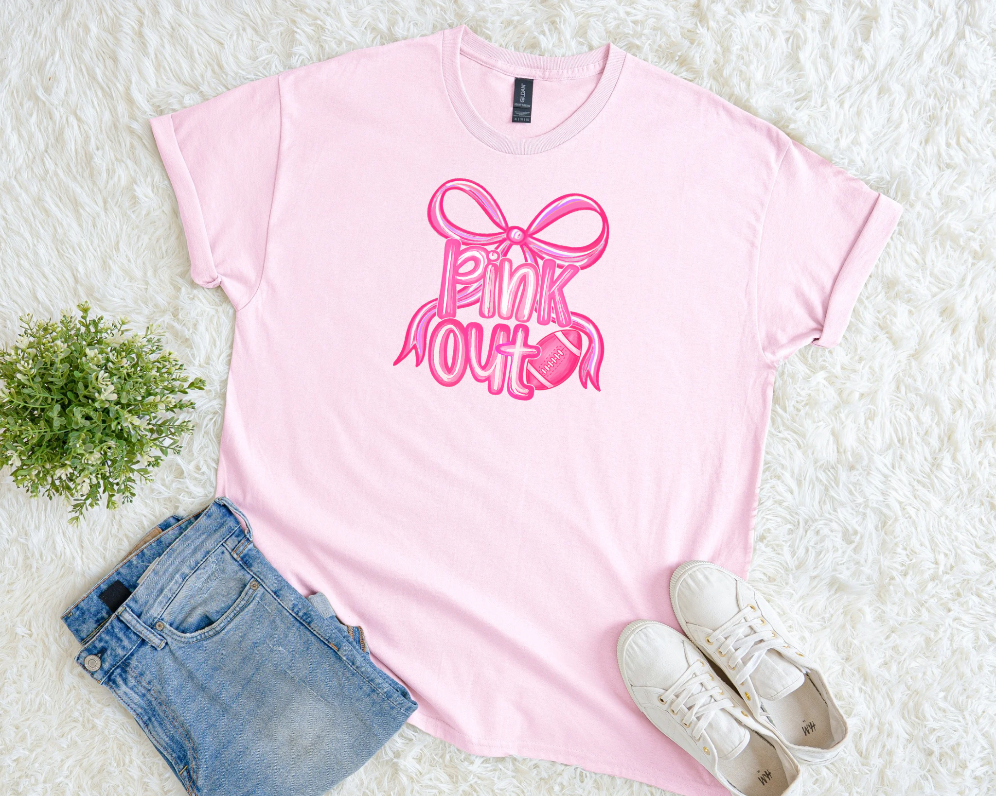 Light pink breast cancer awareness t-shirt with a pink ribbon bow and football graphic and the phrase “Pink Out.