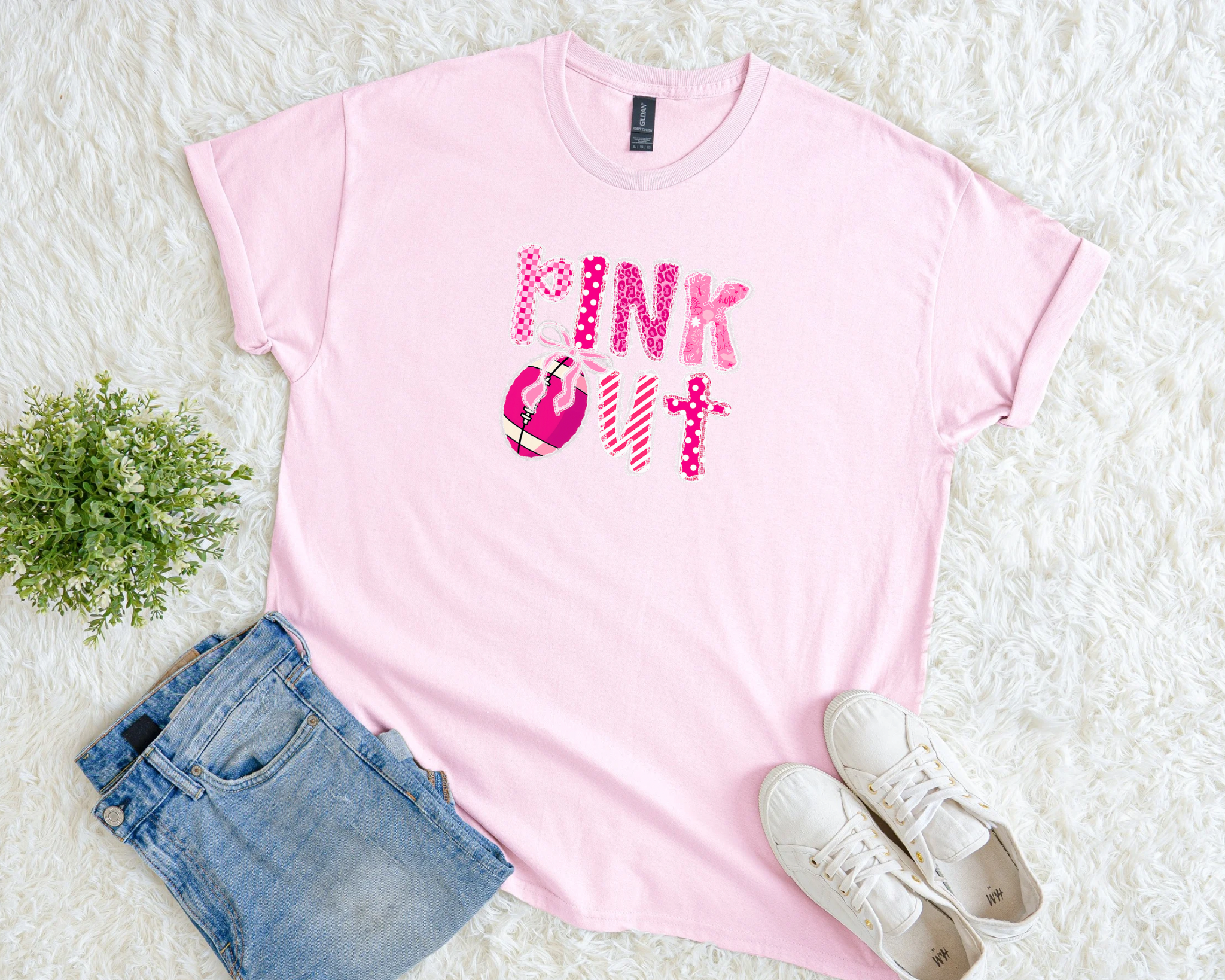 Light pink breast cancer awareness t-shirt with bold patterned “Pink Out” lettering, football graphic, and pink ribbon detail.