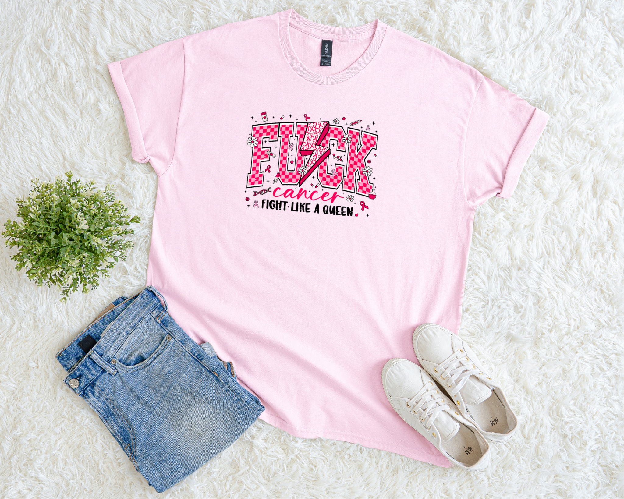 Pink t-shirt with graphic design on a white surface with denim shorts and white sneakers.