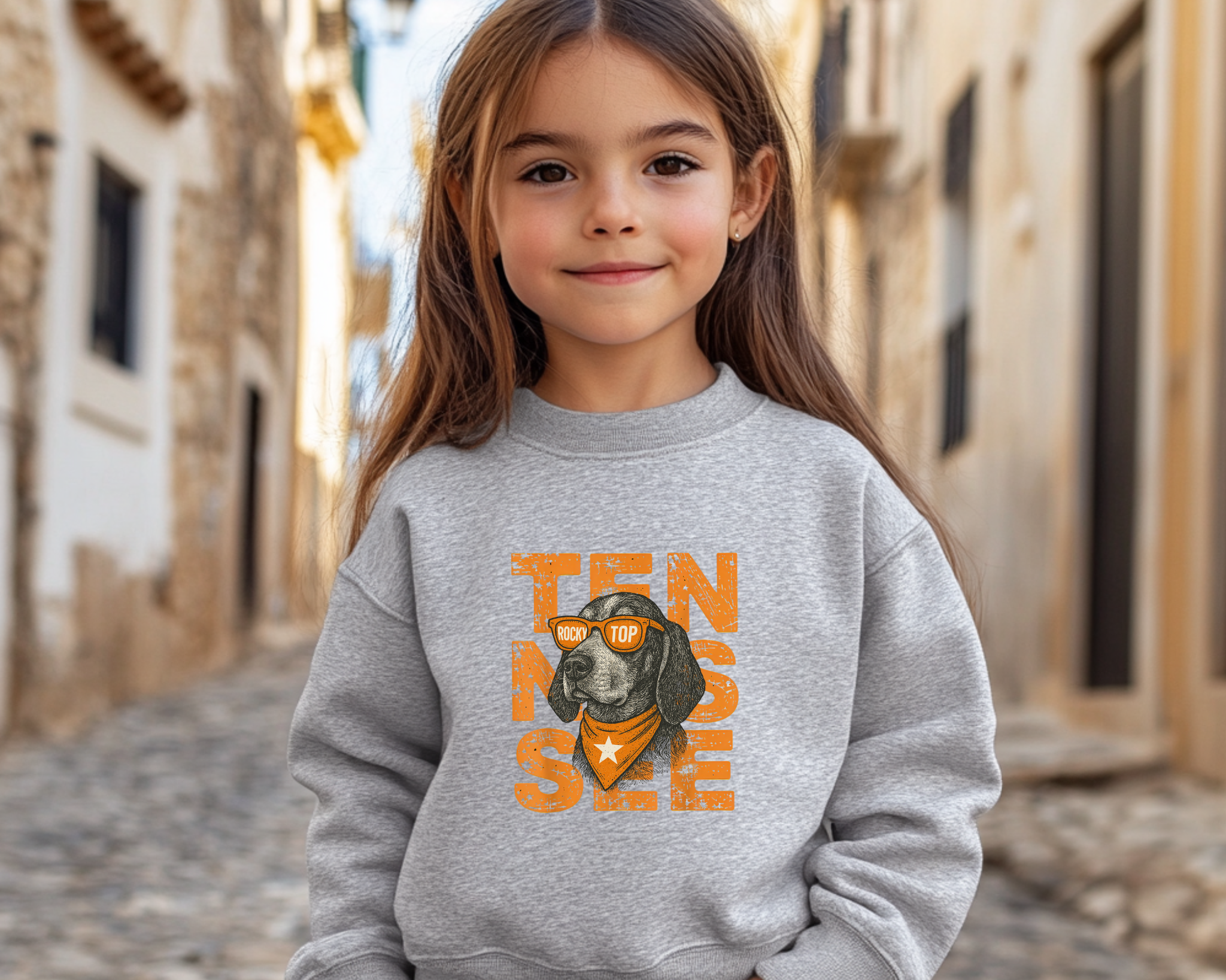 Child wearing a gray sweatshirt with a dog graphic and 'TENNESSEE' text in an outdoor setting.