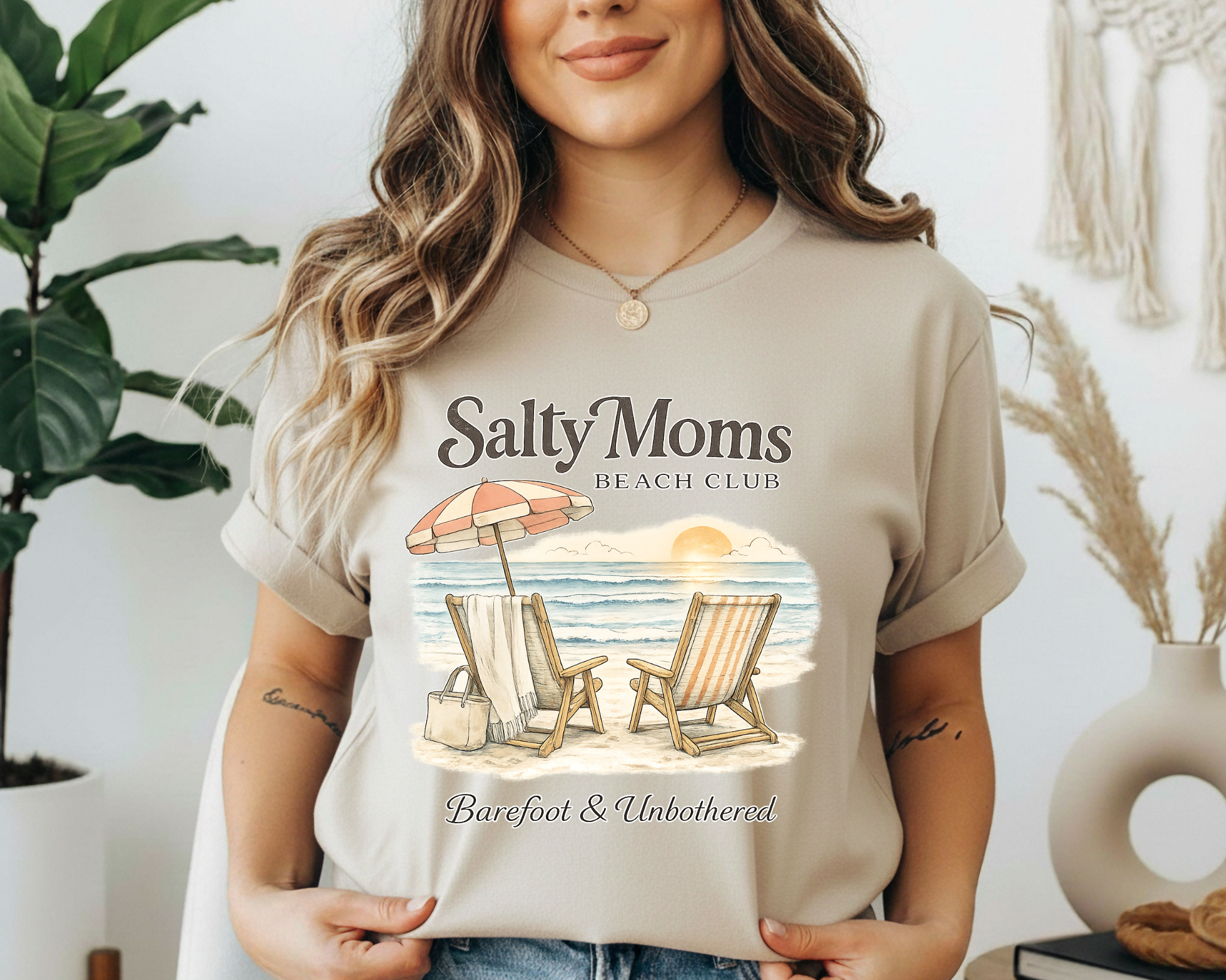 Woman wearing a 'Salty Moms Beach Club' t-shirt with a beach graphic.
