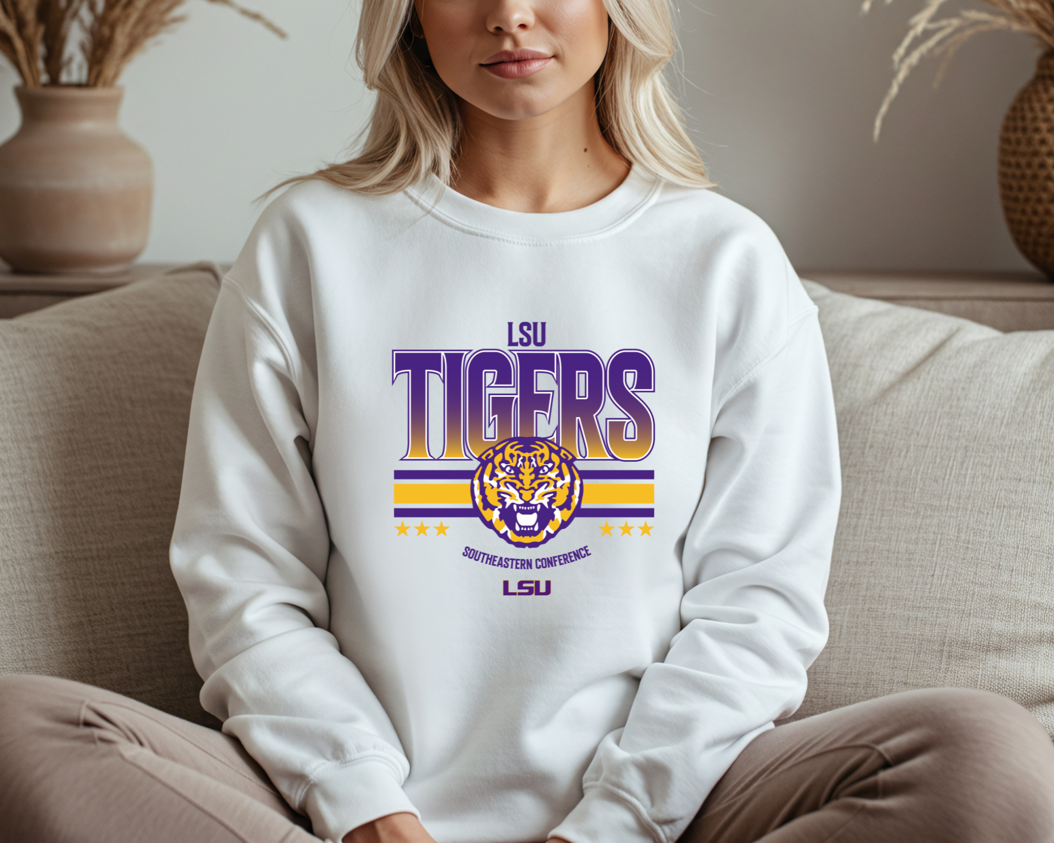 A woman wearing an LSU Tigers-inspired crewneck sweatshirt with bold purple and gold graphics featuring a tiger design, sitting comfortably and ready for game day.