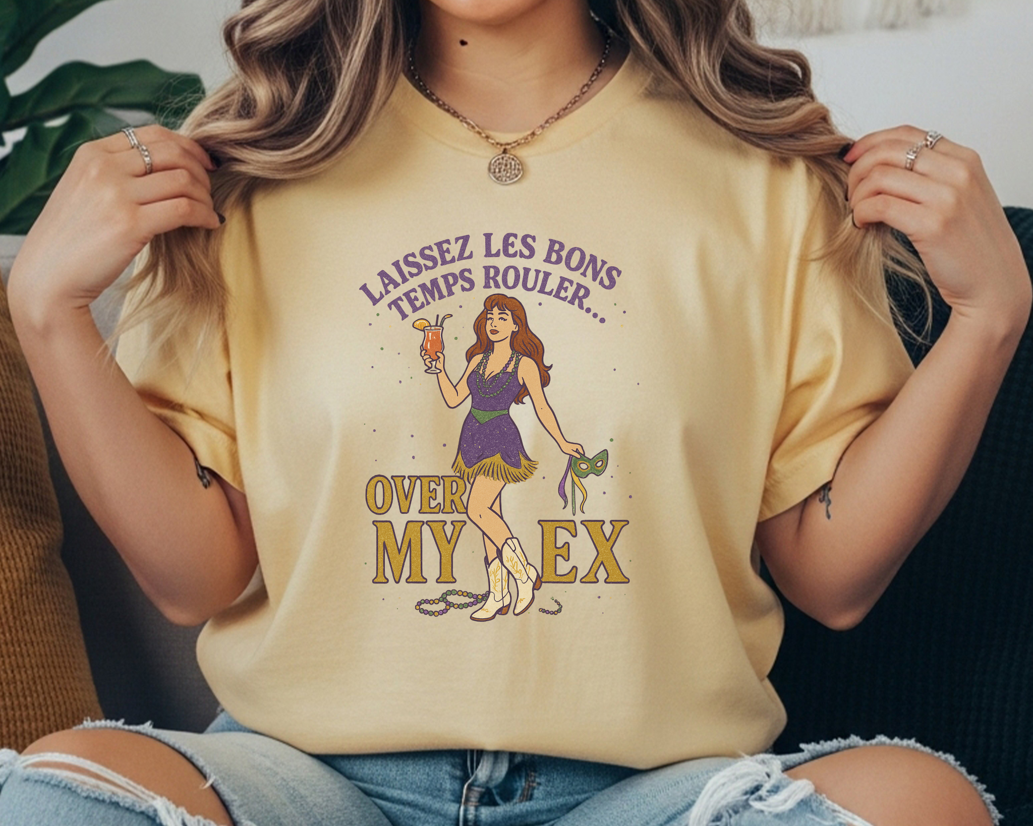 butter Comfort Colors tee featuring Mardi Gras design with cowgirl holding a mask and drink, text reads “Laissez Les Bons Temps Rouler Over My Ex.”