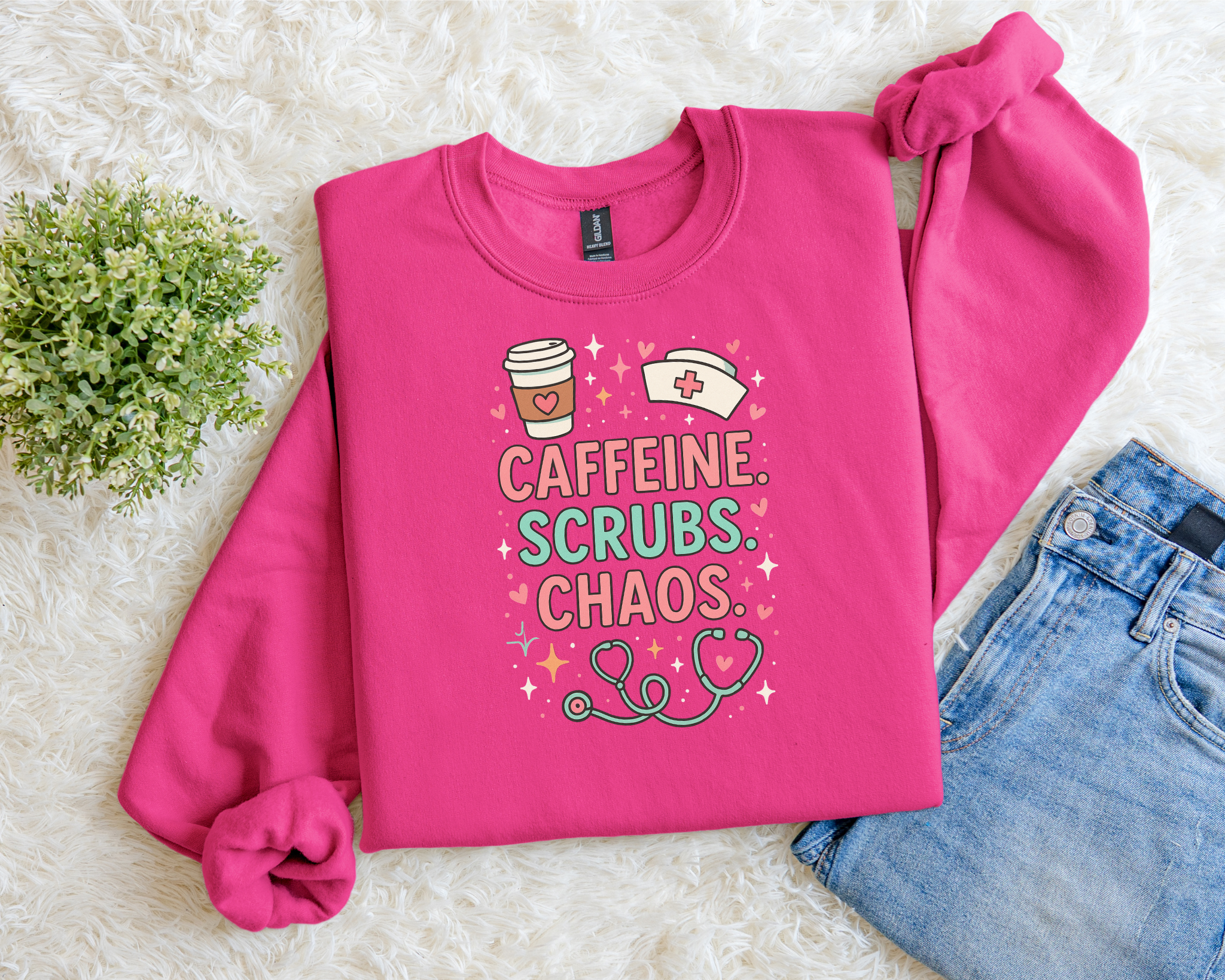Pink sweatshirt with 'Caffeine. Scrubs. Chaos.' text on a light background