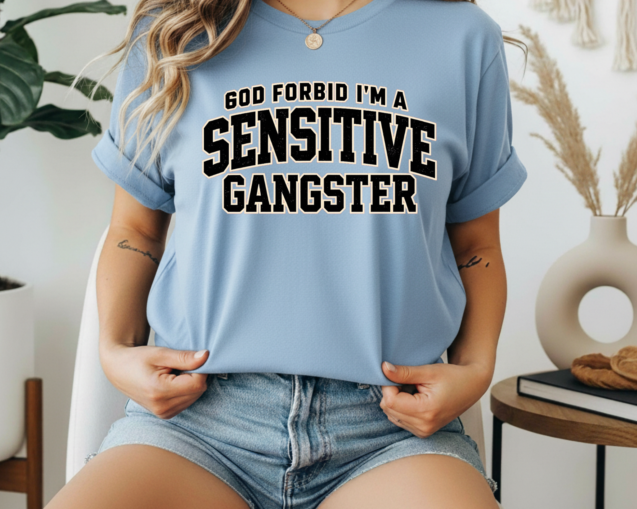 Person wearing a blue t-shirt with text 'GOD FORBID I'M A SENSITIVE GANGSTER' in a casual setting.