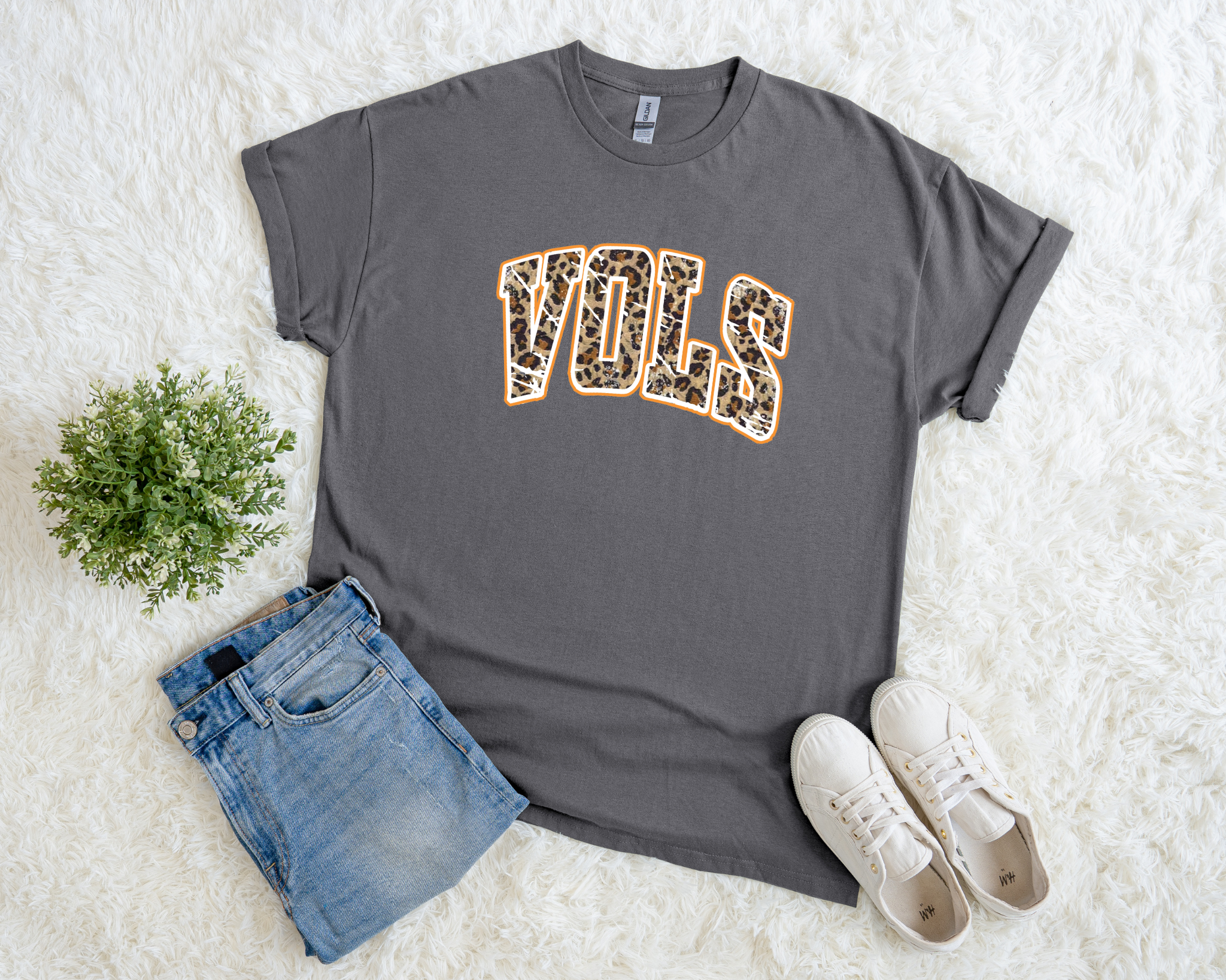 charcoal t-shirt with leopard print “VOLS” design outlined in orange, styled flat with denim jeans and white sneakers.