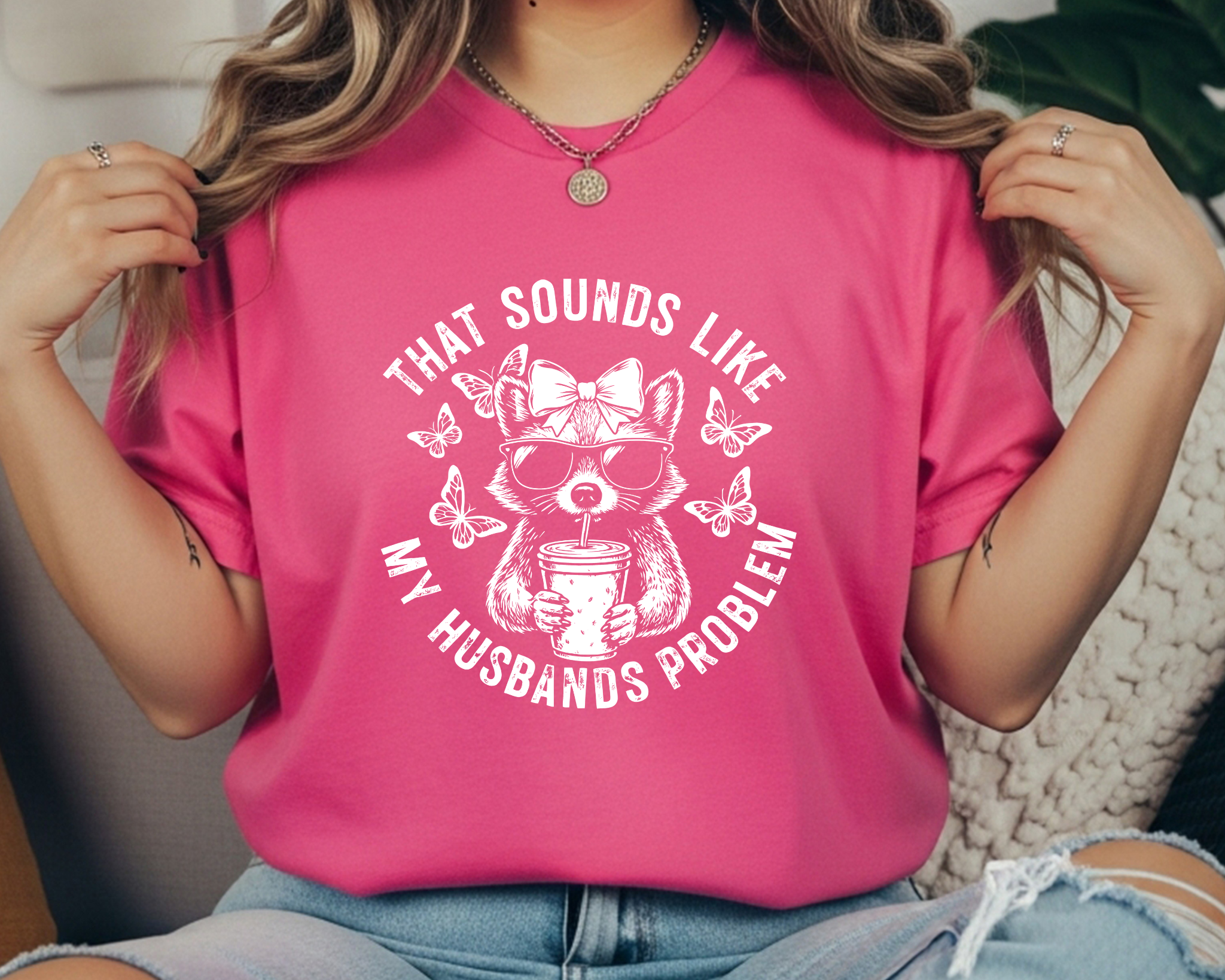 Comfort Colors t-shirt featuring a funny raccoon graphic with sunglasses, bow, iced coffee, and the phrase “That Sounds Like My Husband’s Problem.