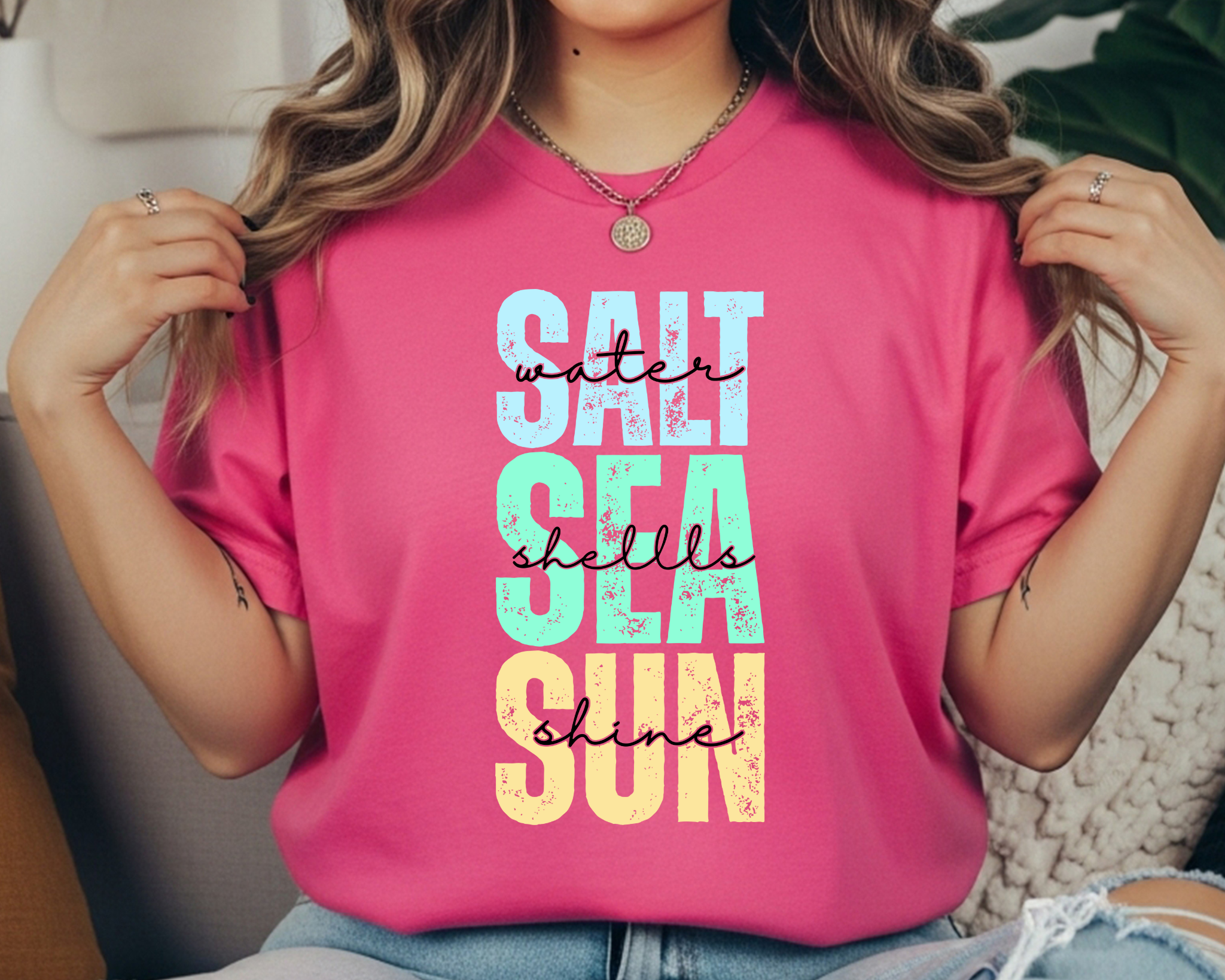 Comfort Colors t-shirt with colorful stacked text reading “SALT WATER SEA SHELLS SUNSHINE” with black script overlay.