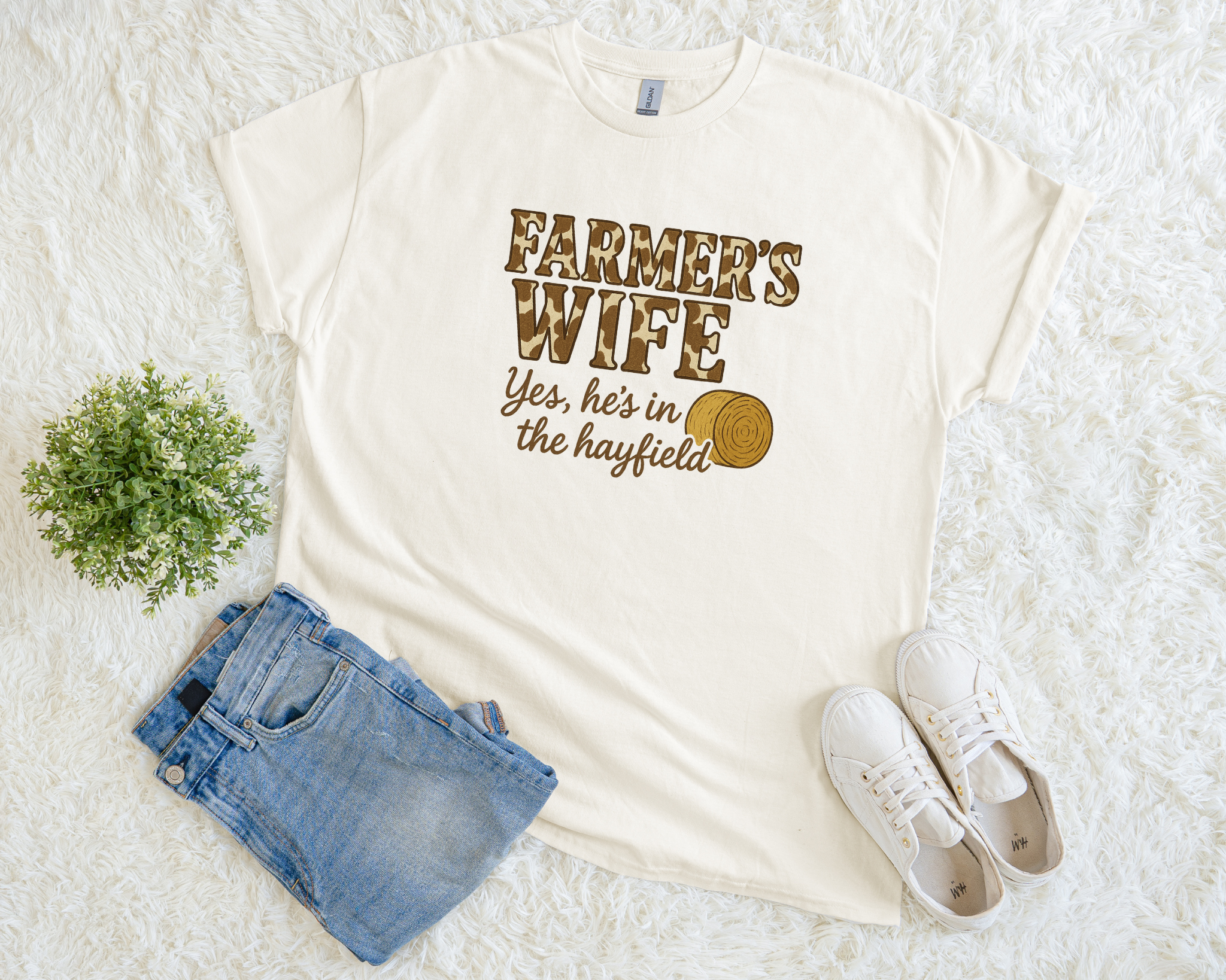 White t-shirt with 'Farmer's Wife' text, denim shorts, and white sneakers on a light background