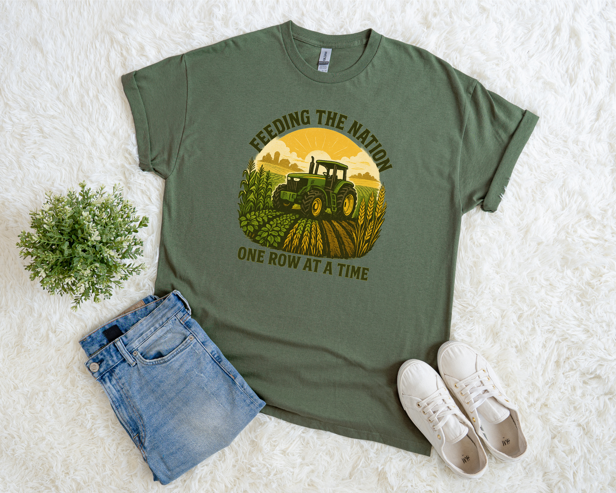 Green t-shirt with tractor graphic and text, paired with denim shorts and white sneakers on a white background