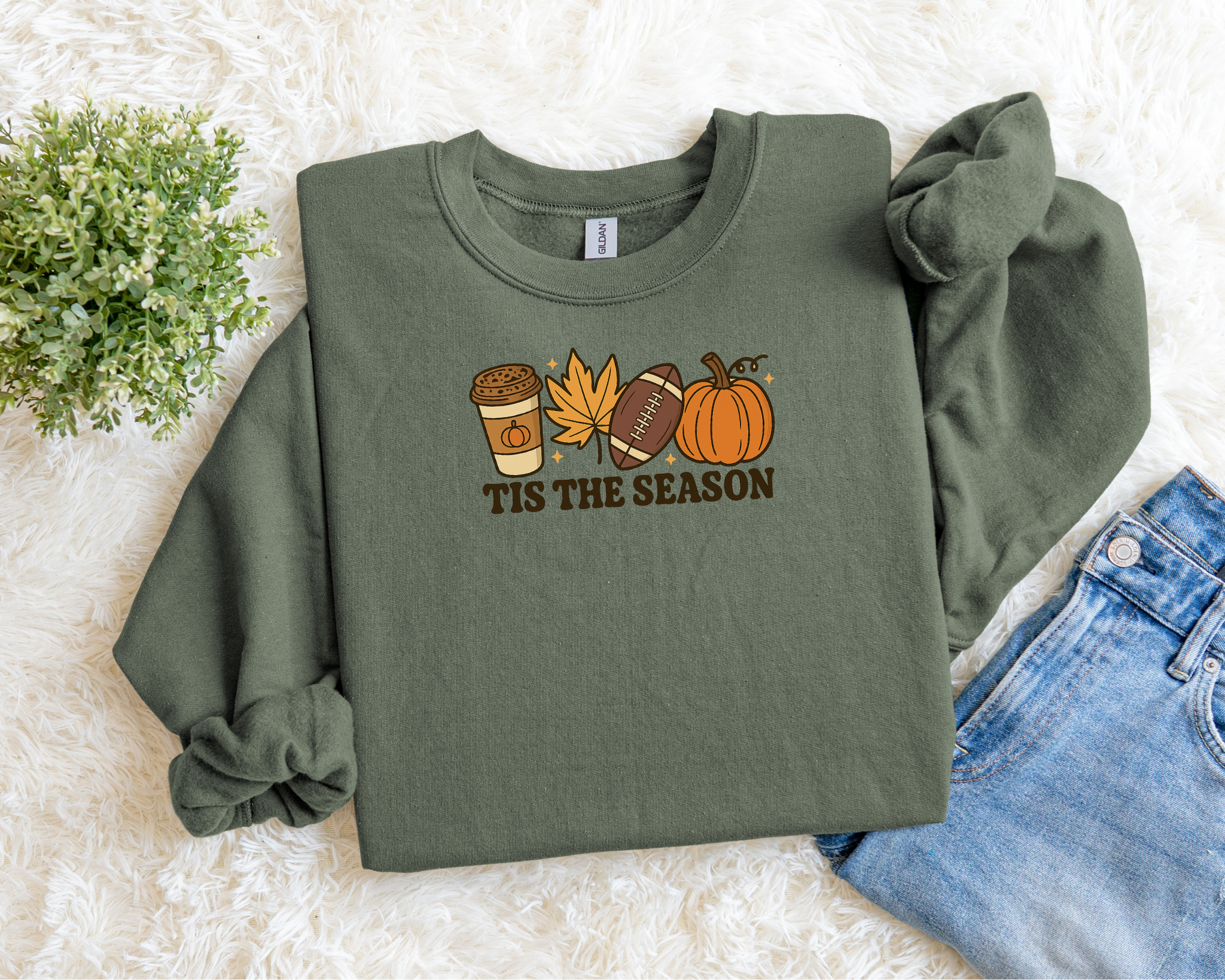 Green sweatshirt with 'TIS THE SEASON' text and autumn-themed graphics on a light background.