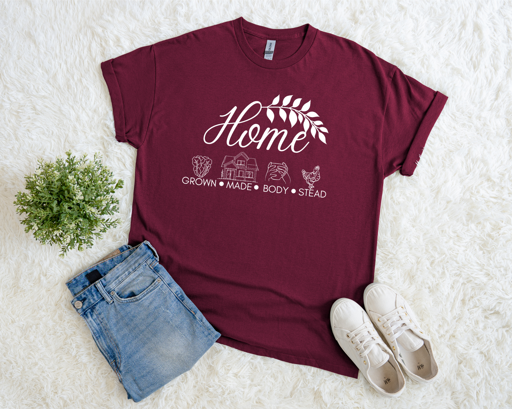 Maroon t-shirt with 'Home' graphic design on a white surface with denim shorts and white sneakers.