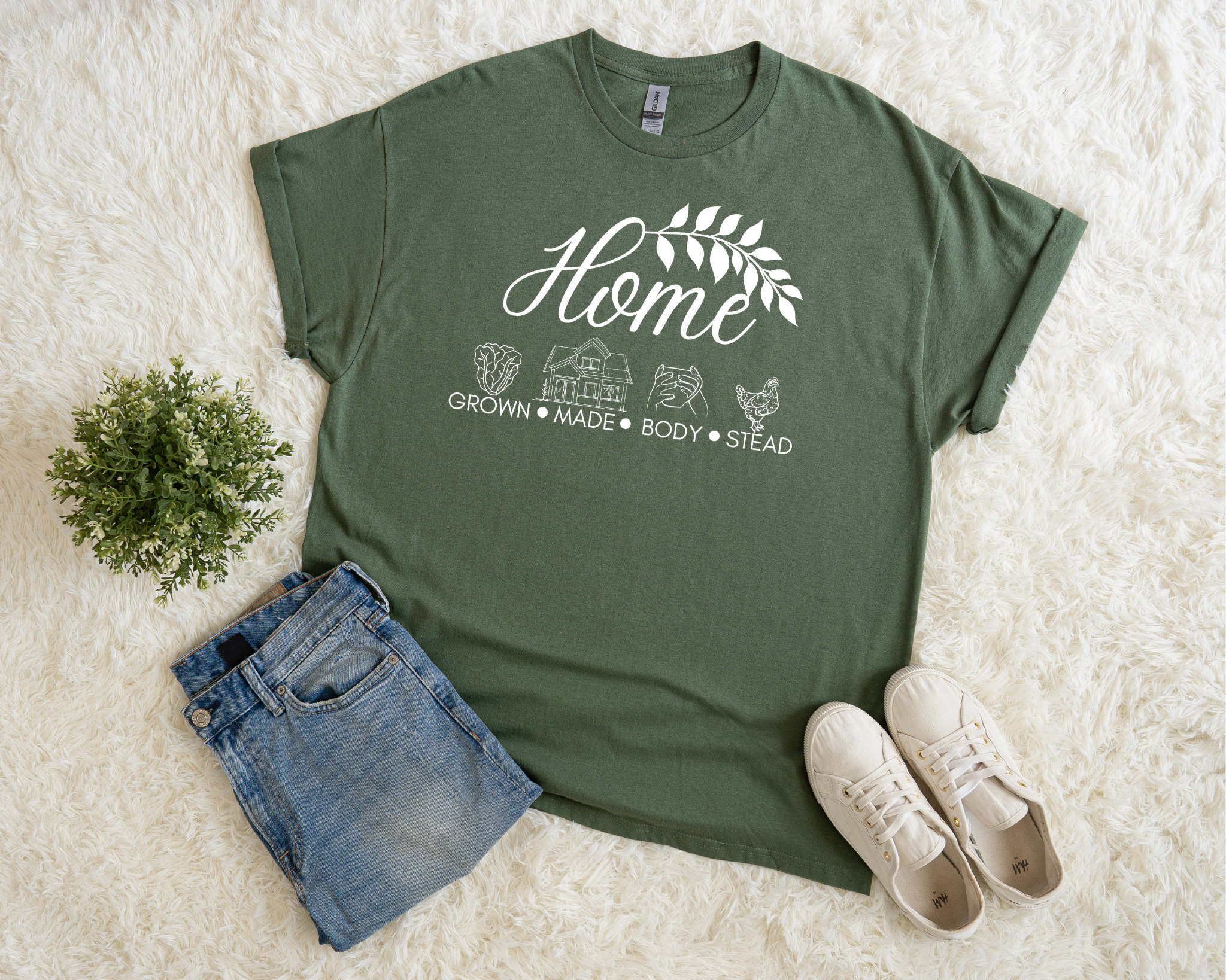 Green t-shirt with 'Home' graphic design on a white surface with jeans and sneakers.
