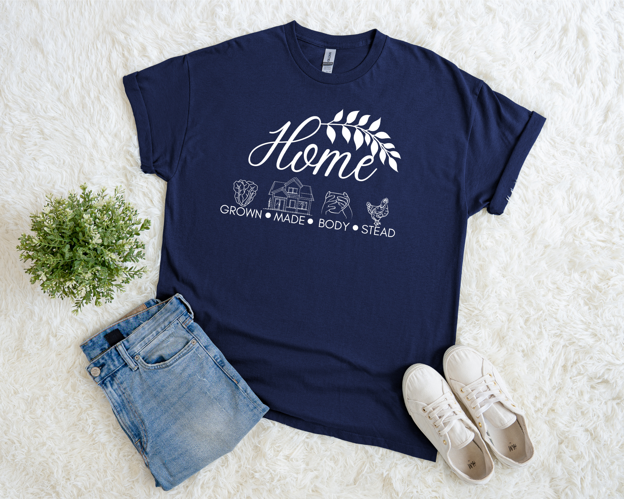 Navy blue t-shirt with 'Home' graphic design on a white surface with denim shorts and white sneakers.