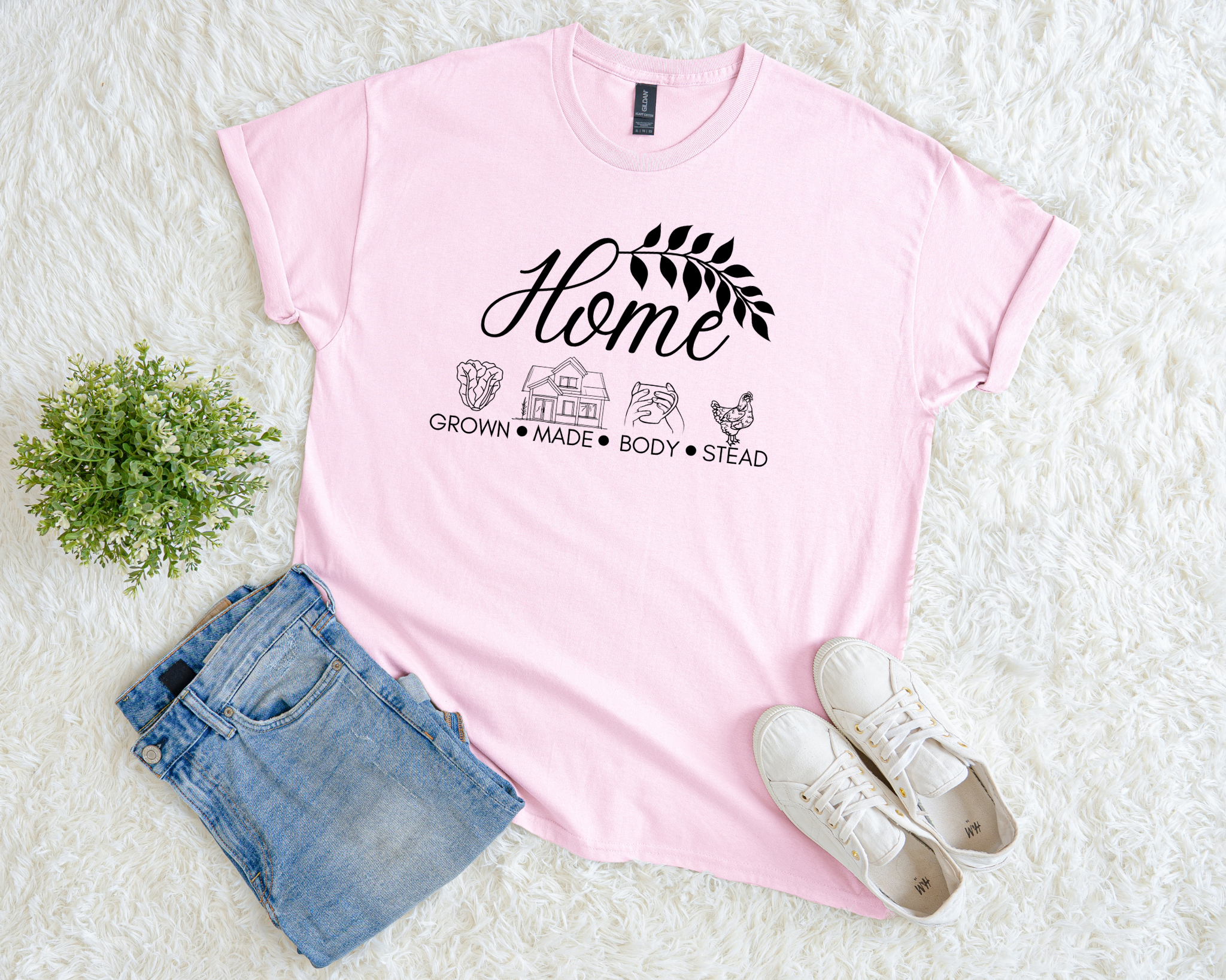 Pink t-shirt with text and graphics on a white surface with denim shorts and white sneakers.