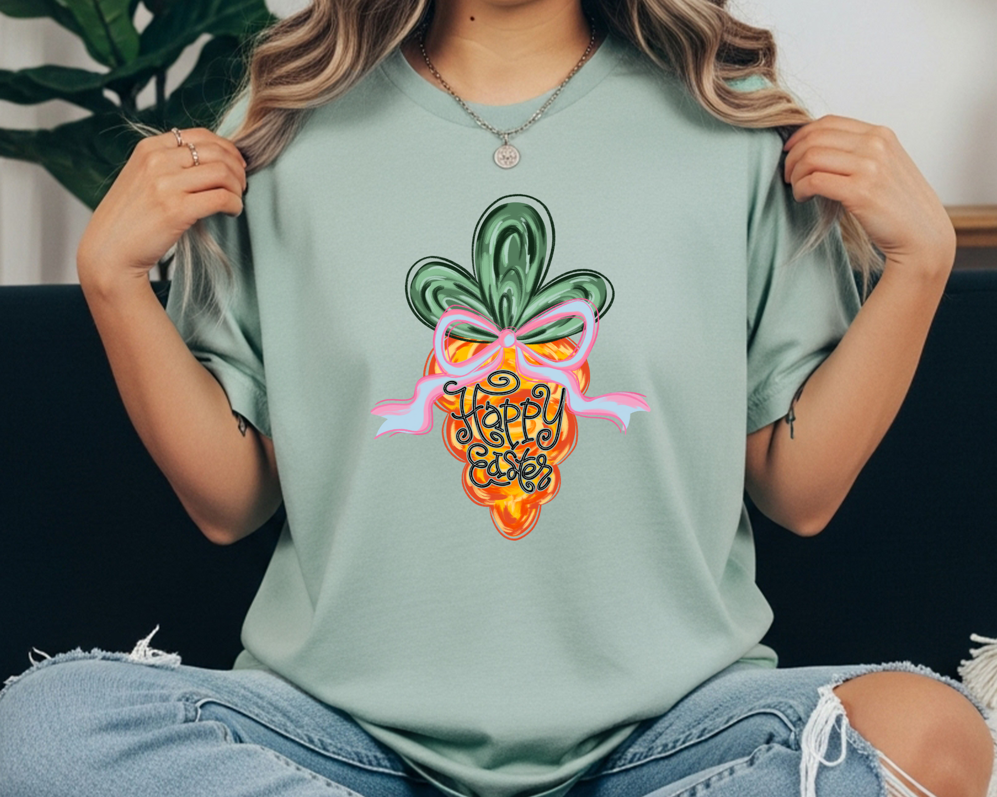 Comfort Colors t-shirt featuring a colorful carrot graphic with a pink bow and hand-lettered “Happy Easter” text in the center.