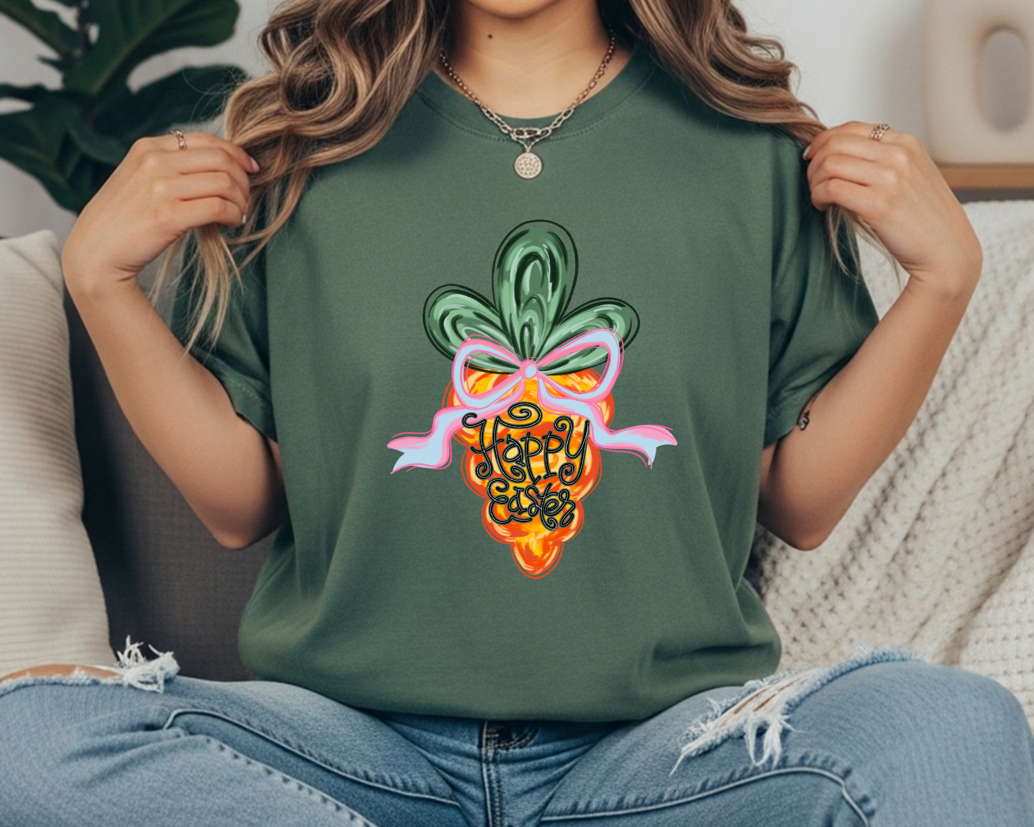 Comfort Colors t-shirt featuring a colorful carrot graphic with a pink bow and hand-lettered “Happy Easter” text in the center.