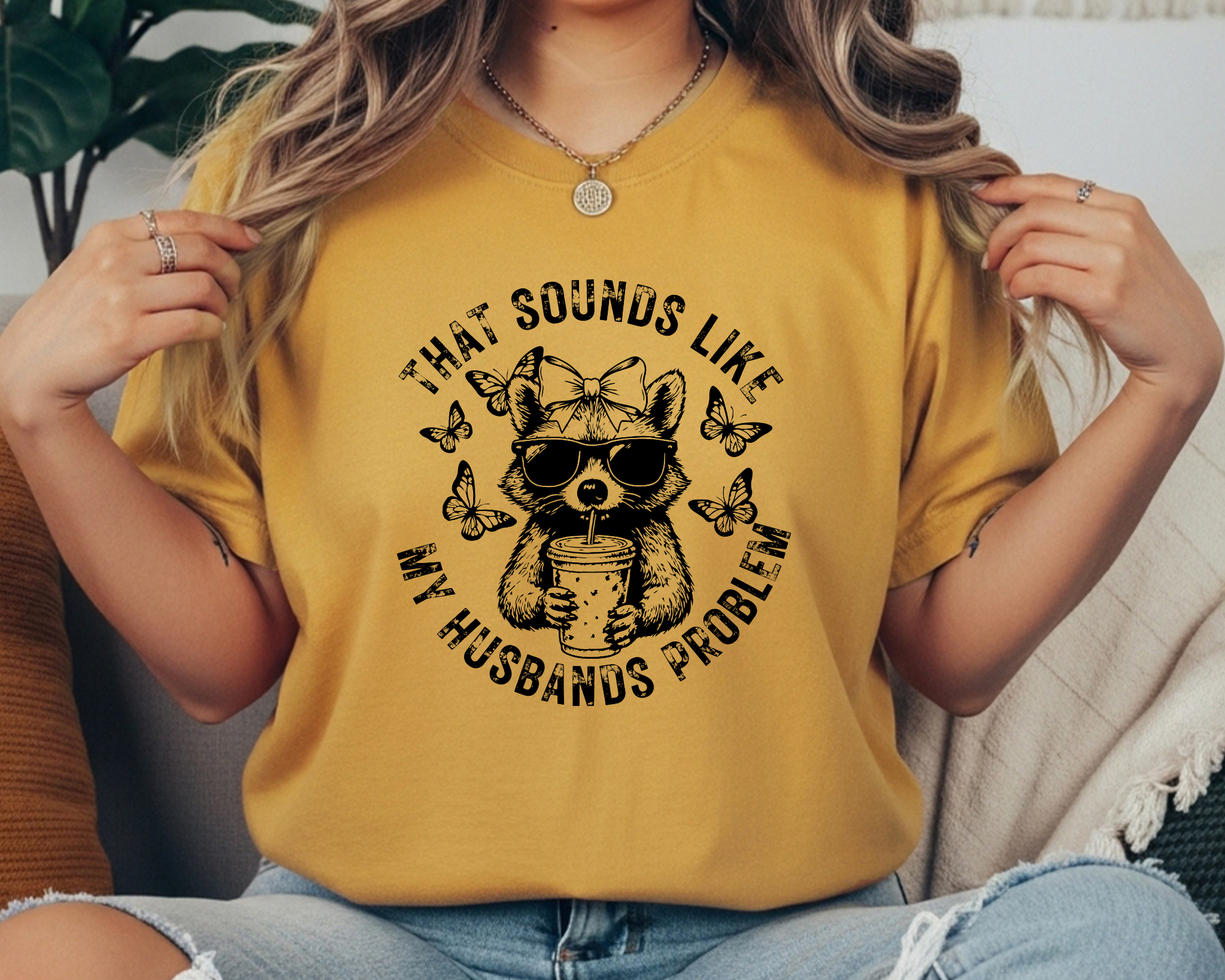 Comfort Colors t-shirt featuring a funny raccoon graphic with sunglasses, bow, iced coffee, and the phrase “That Sounds Like My Husband’s Problem.