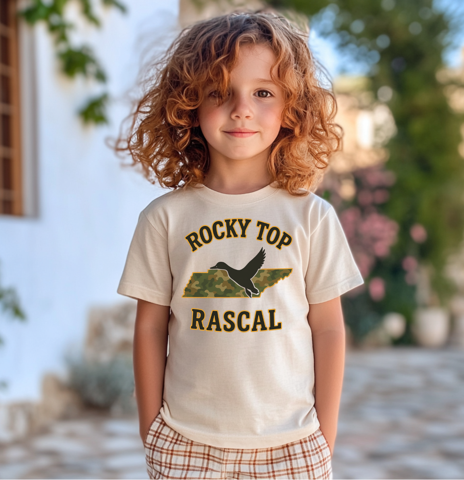 Smiling young boy wearing a t-shirt with “Rocky Top Rascal” text and camo Tennessee state design featuring a duck silhouette.