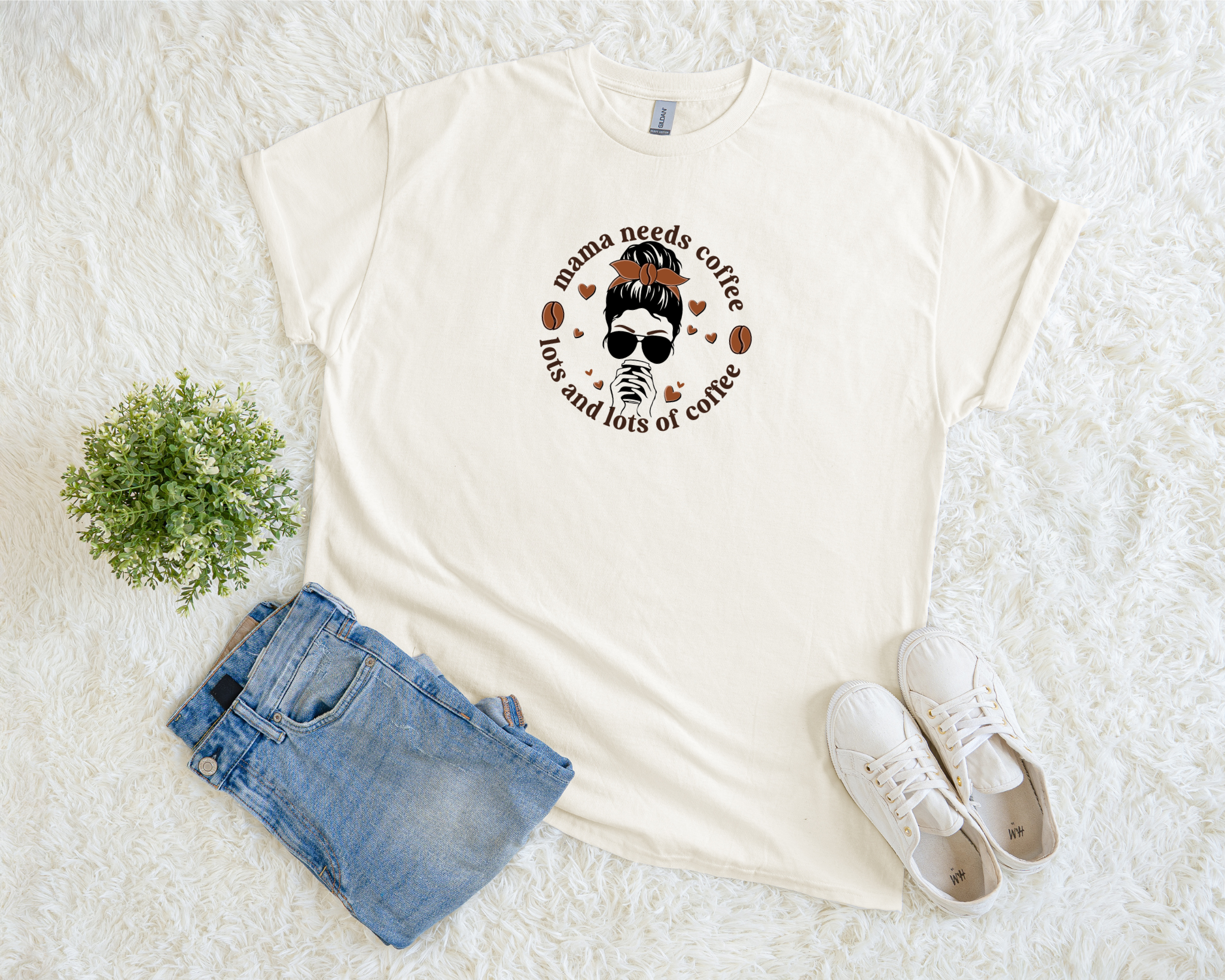 t-shirt featuring a stylish mom graphic with sunglasses, messy bun, and coffee cup, surrounded by the phrase “Mama Needs Lots and Lots of Coffee.