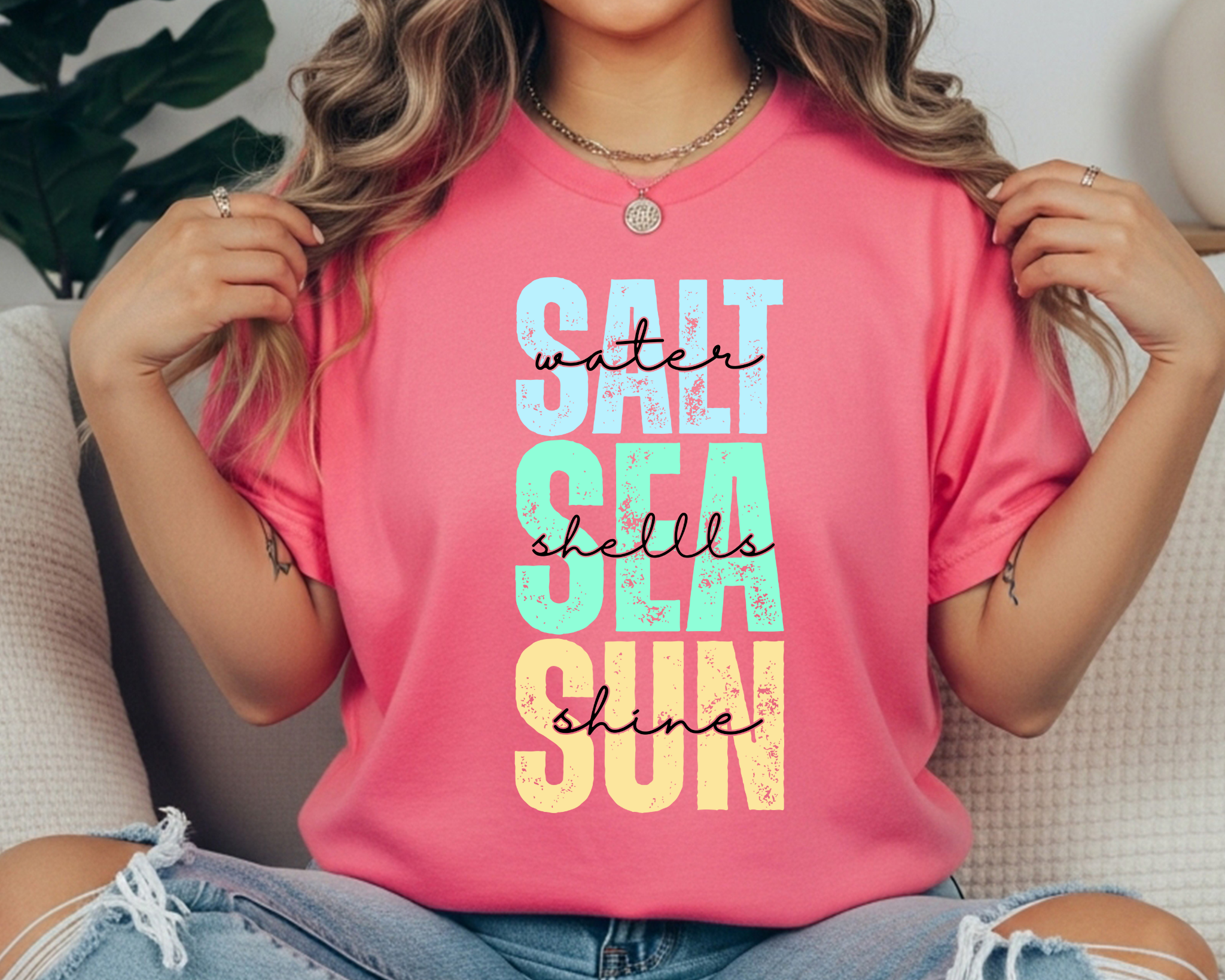 Comfort Colors t-shirt with colorful stacked text reading “SALT WATER SEA SHELLS SUNSHINE” with black script overlay.
