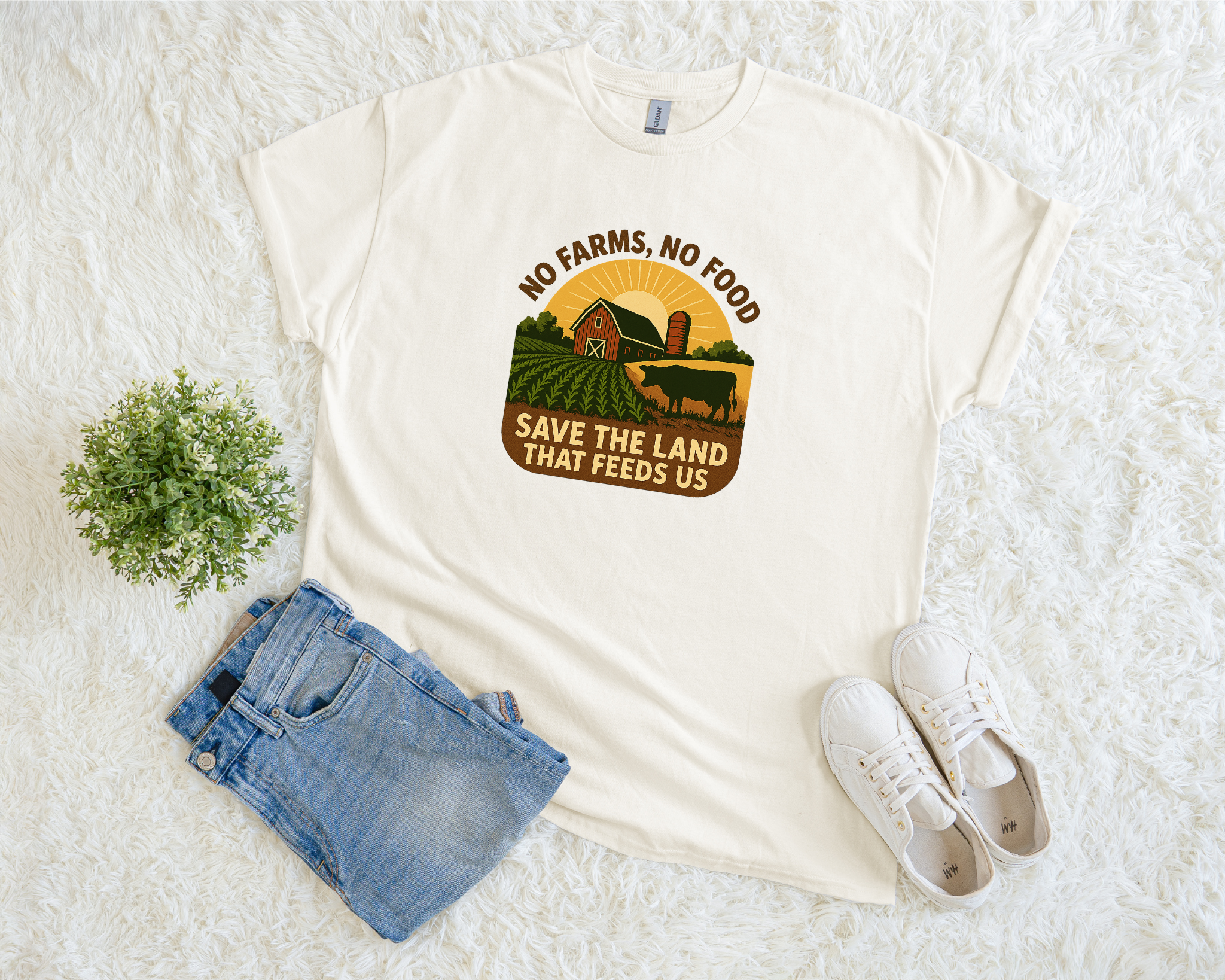 White t-shirt with a graphic design, blue jeans, and white sneakers on a white surface.