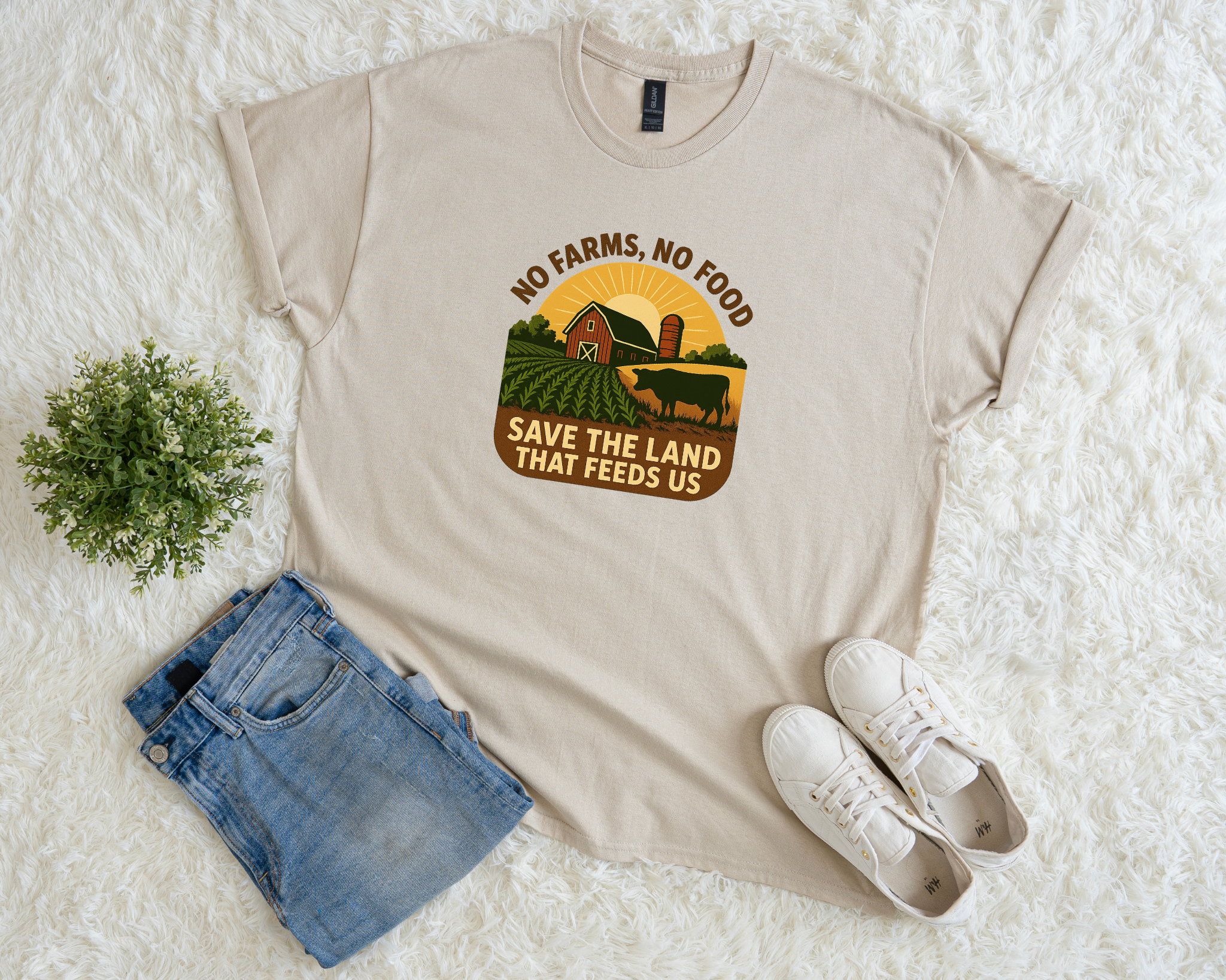 Beige t-shirt with a graphic and text on a white surface with shorts and sneakers.