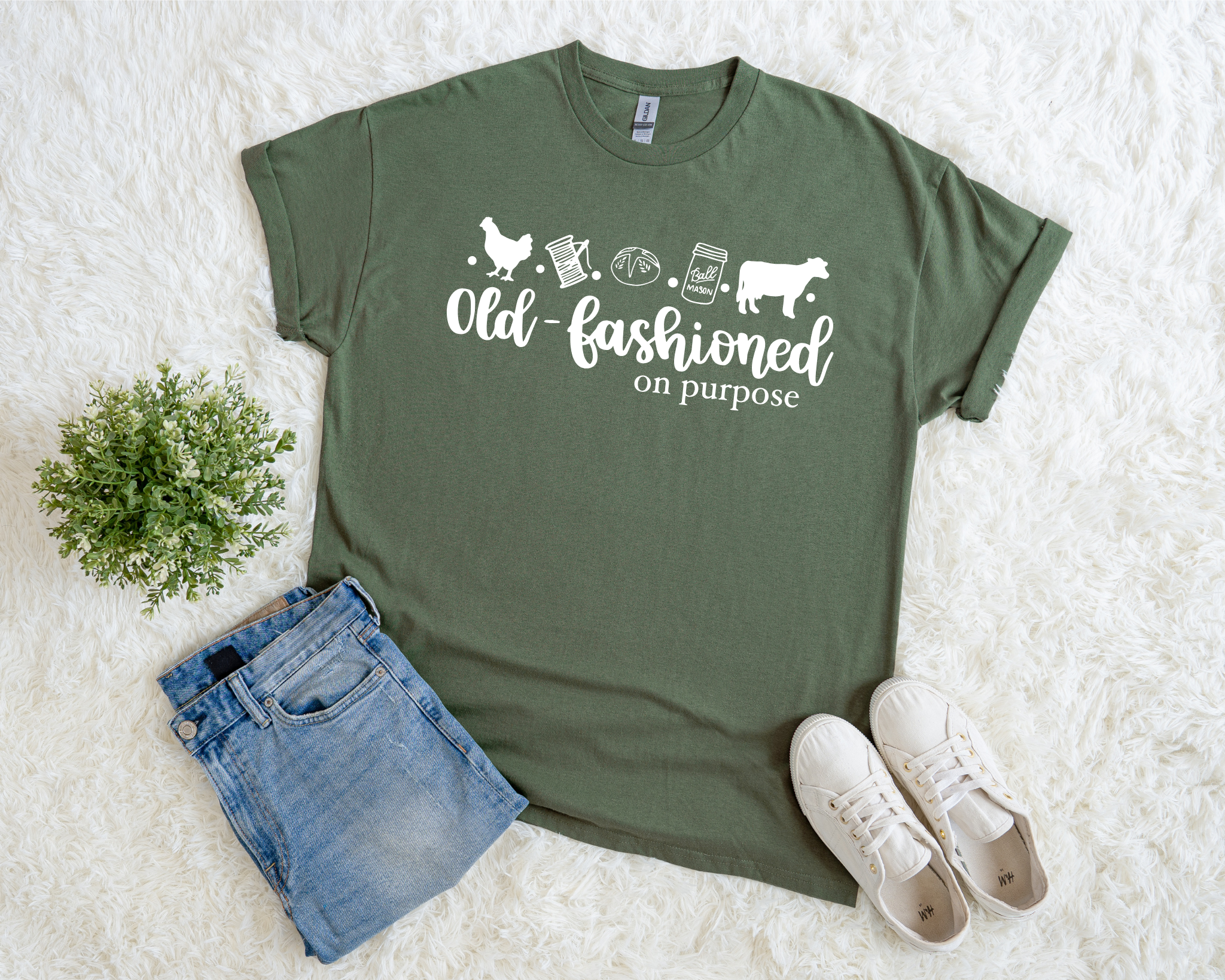 Green t-shirt with text and graphics on a white surface with jeans and sneakers.