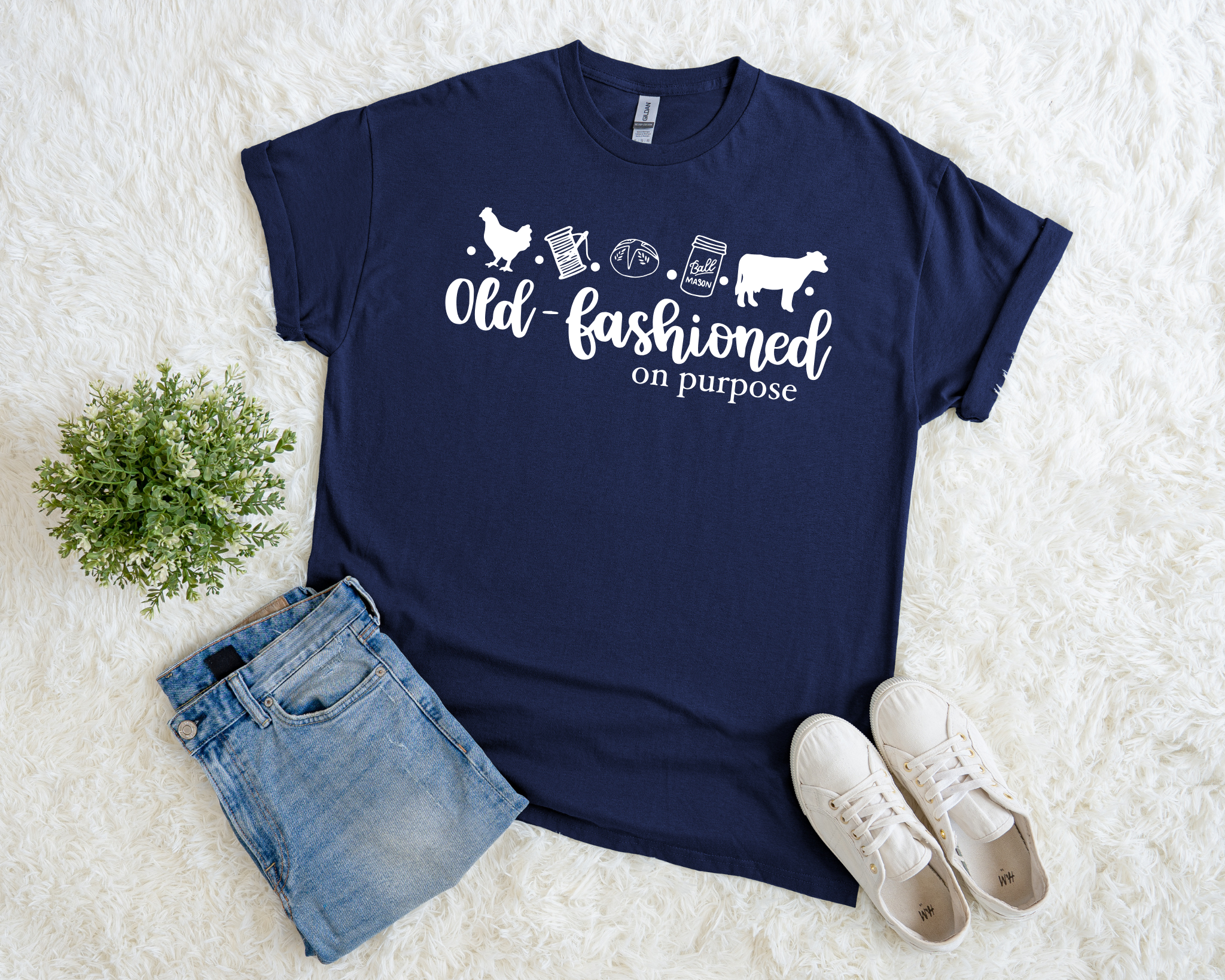 Navy blue t-shirt with white text and graphics on a white surface with denim shorts and white sneakers.