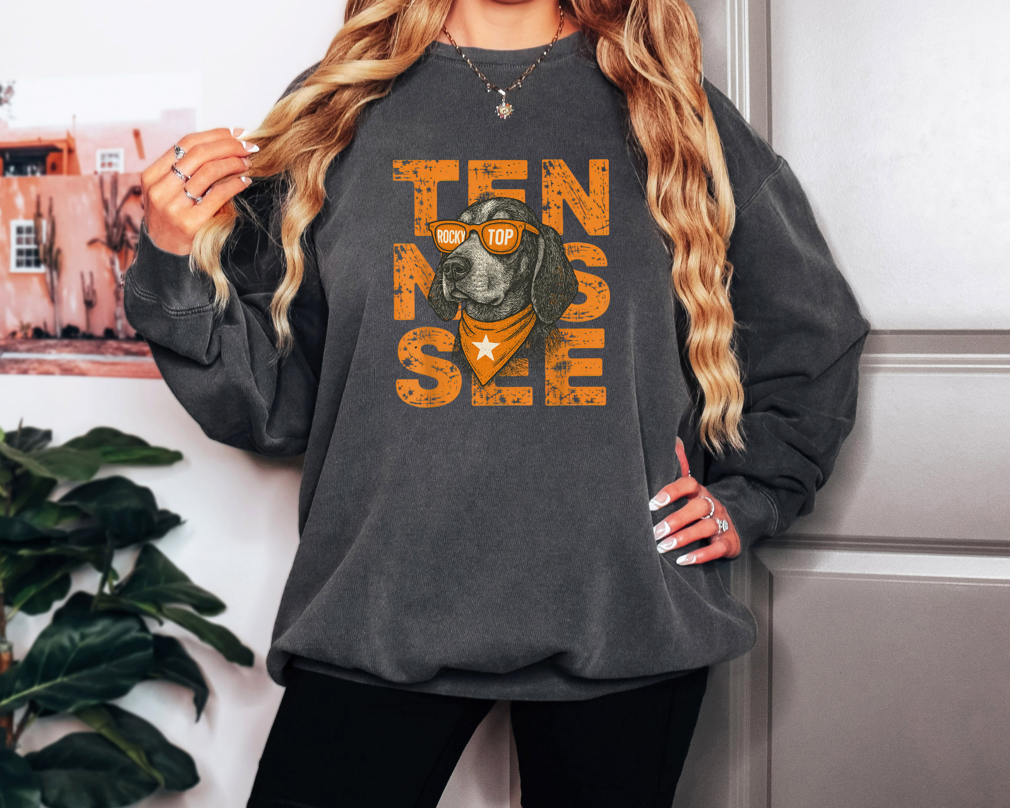 Model wearing a pepper Comfort Colors sweatshirt featuring bold orange TENNESSEE text with smokey wearing “Rocky Top” sunglasses and an orange bandana — retro Southern game-day design.