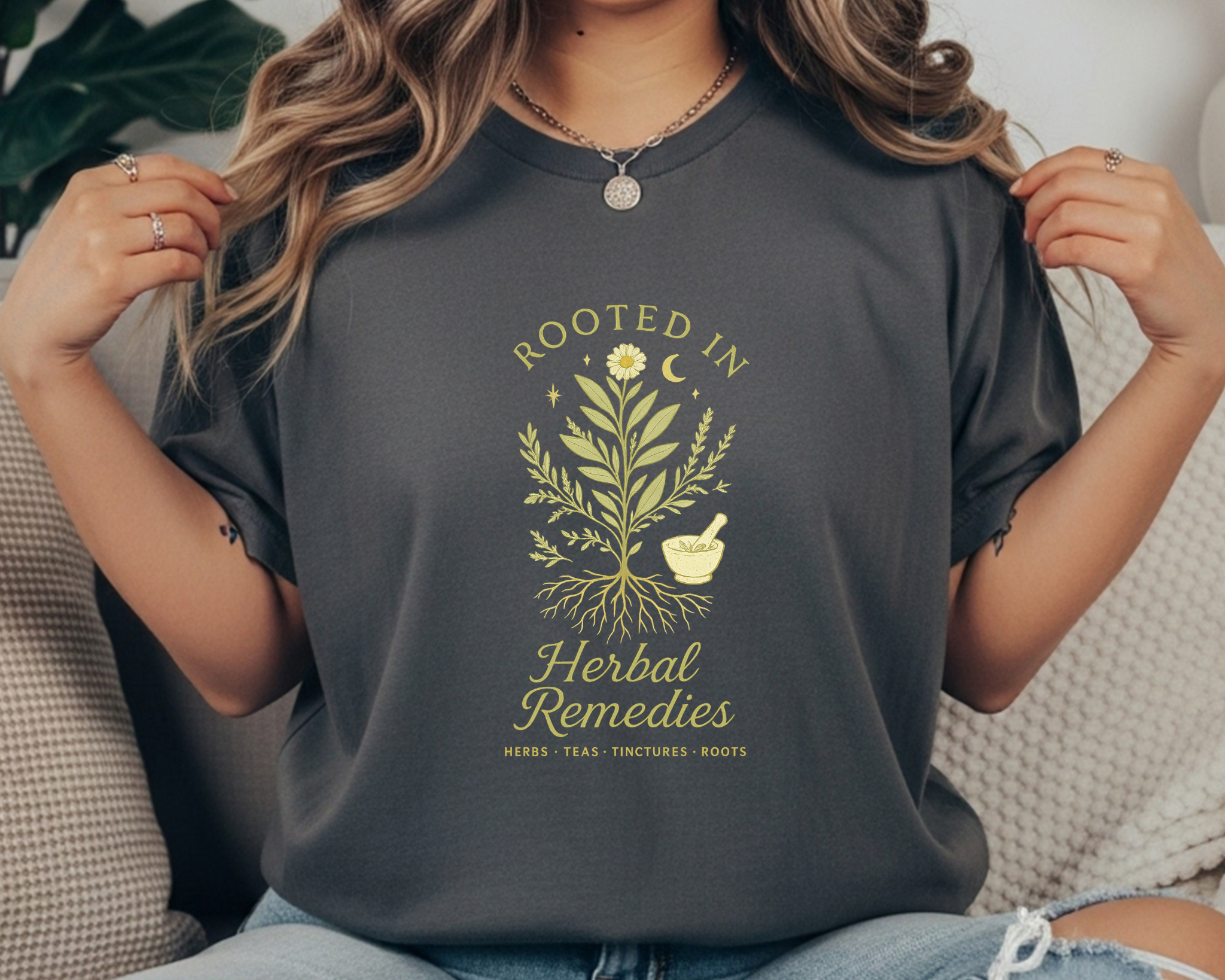 pepper  Comfort Colors t-shirt with a yellow botanical design of herbs and roots, a mortar and pestle, crescent moon, and the text “Rooted in Herbal Remedies – Herbs • Teas • Tinctures • Roots.”