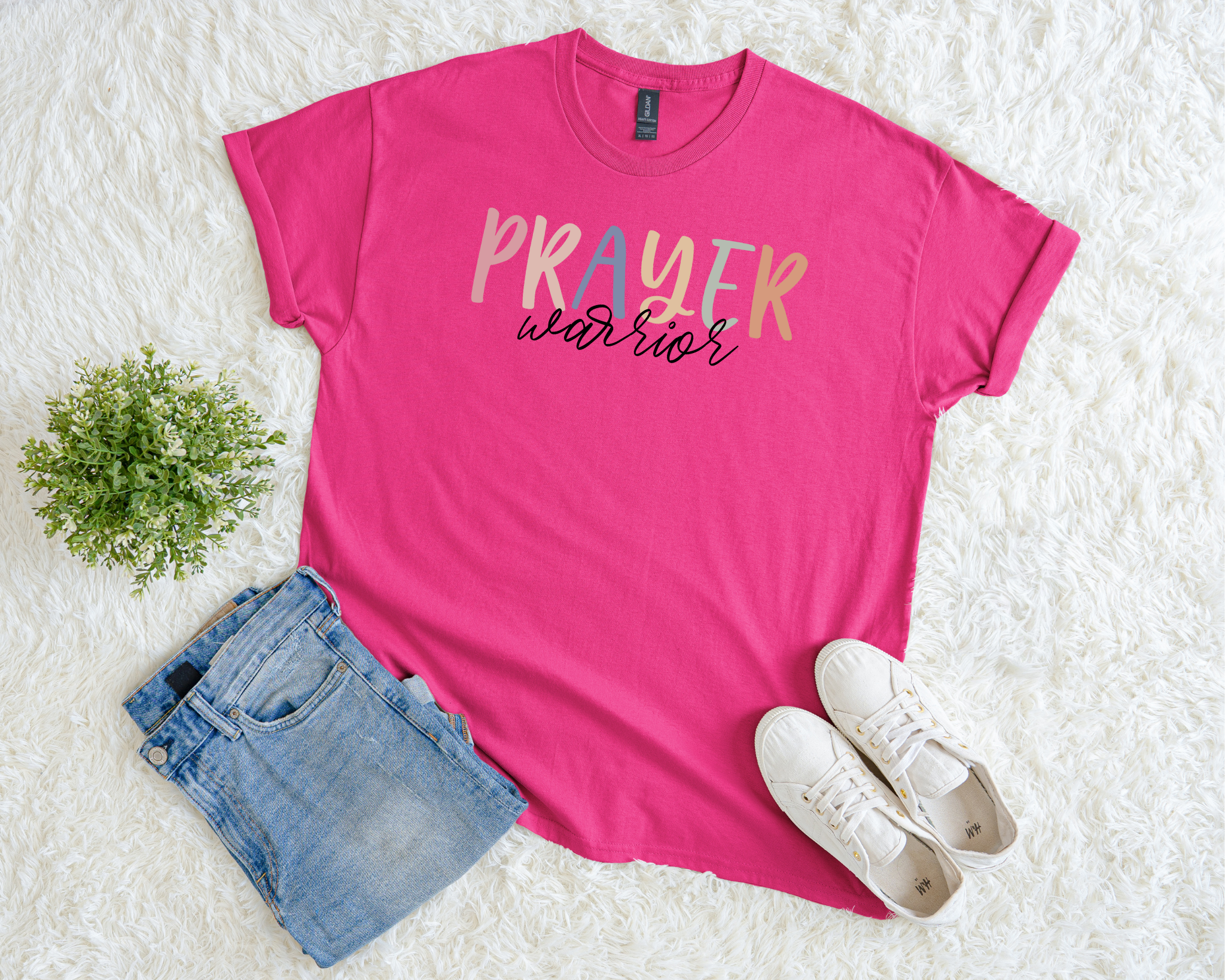 Pink t-shirt with 'PRAYER warrior' text, paired with denim shorts and white sneakers on a light background.
