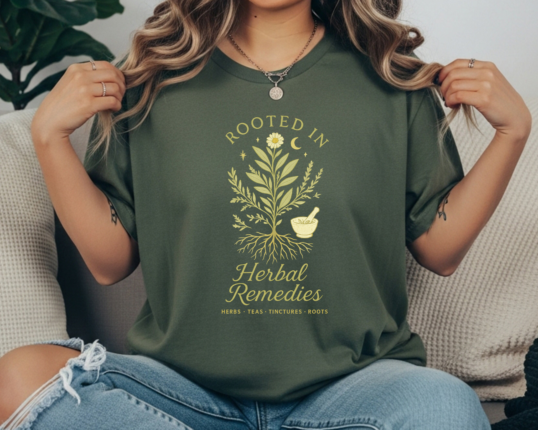 pepper  Comfort Colors t-shirt with a yellow botanical design of herbs and roots, a mortar and pestle, crescent moon, and the text “Rooted in Herbal Remedies – Herbs • Teas • Tinctures • Roots.”