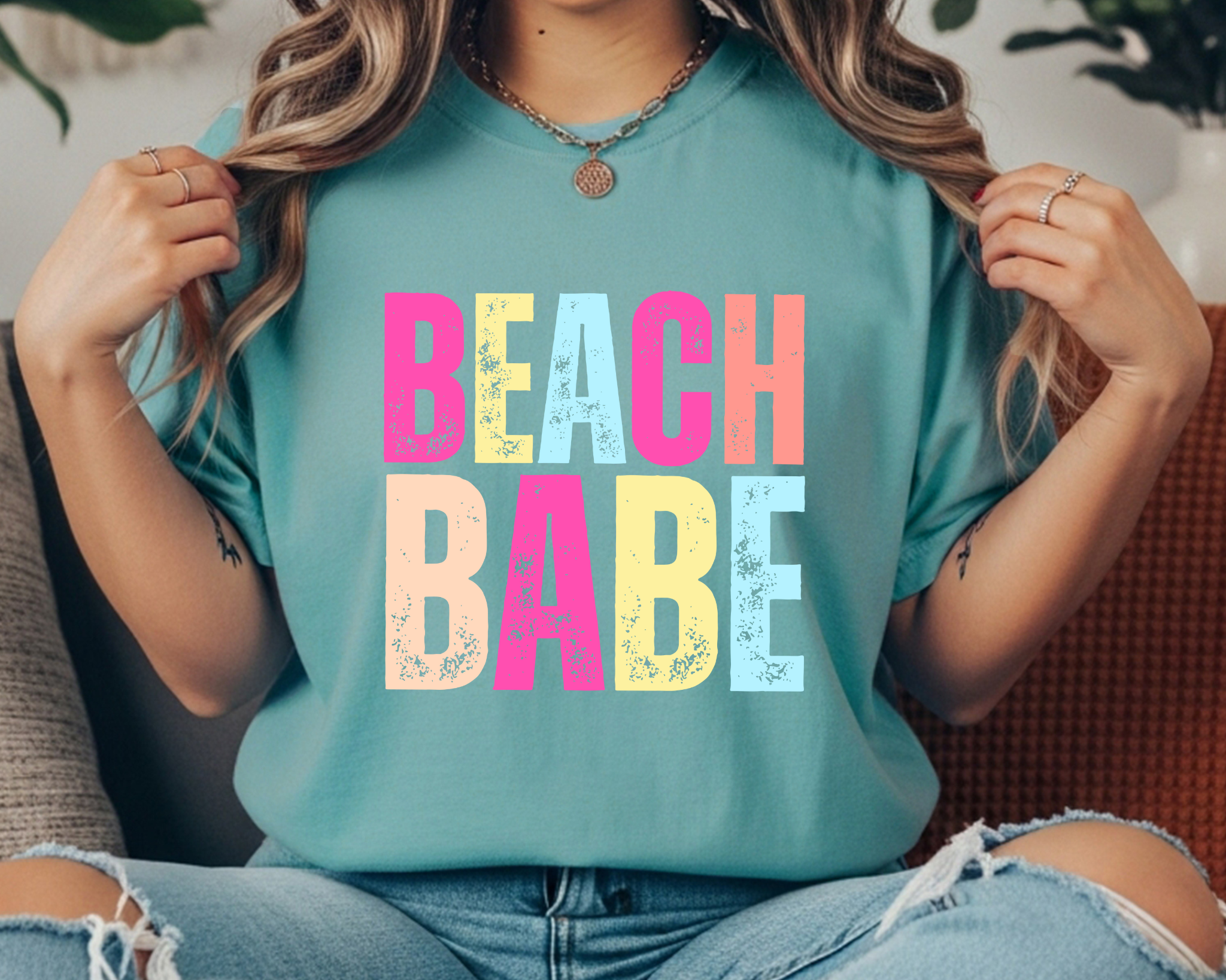 Comfort Colors t-shirt with colorful distressed stacked text that reads “BEACH BABE.”