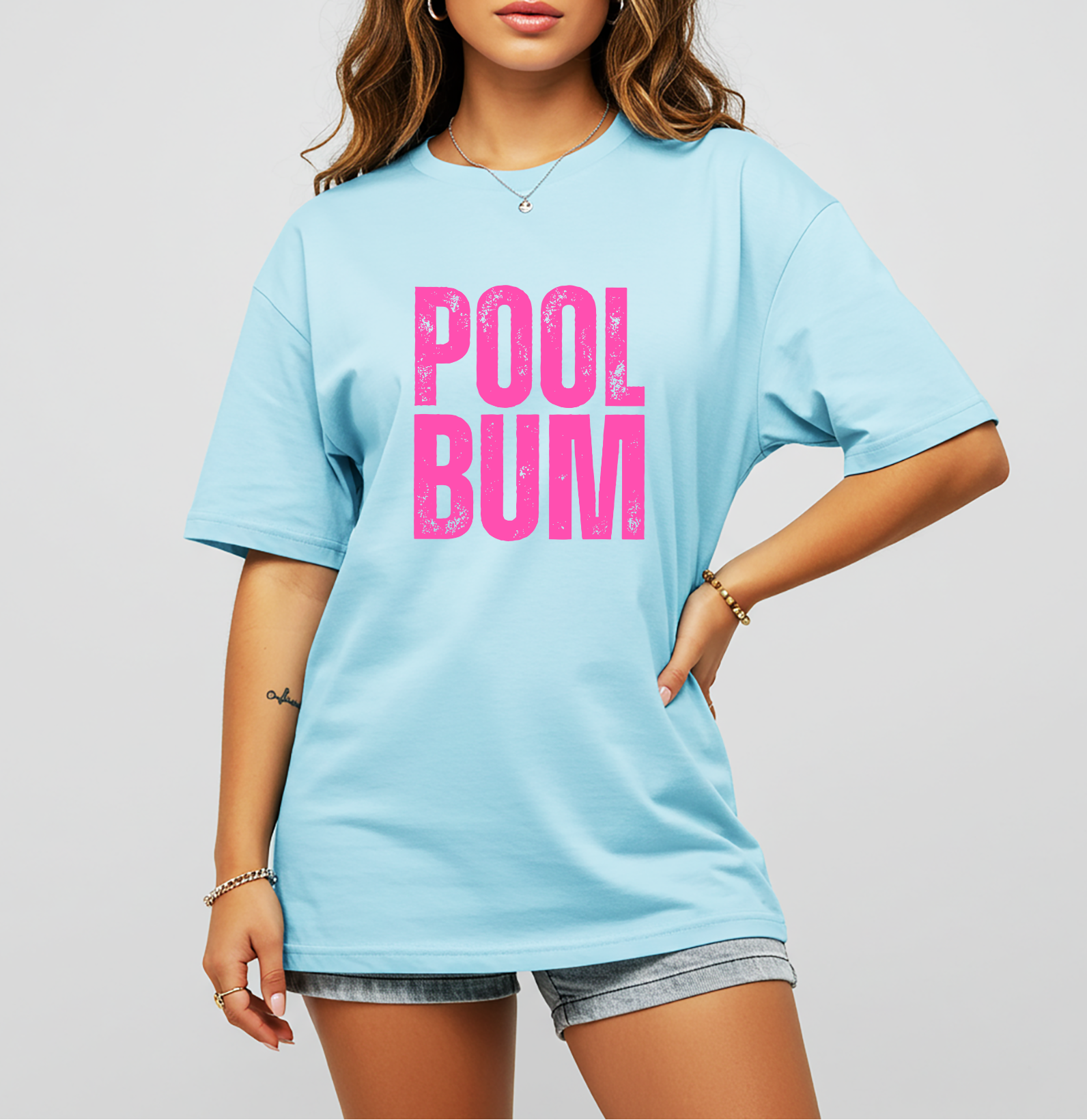 t-shirt with bold pink distressed “POOL BUM” text on the front, styled with denim shorts.