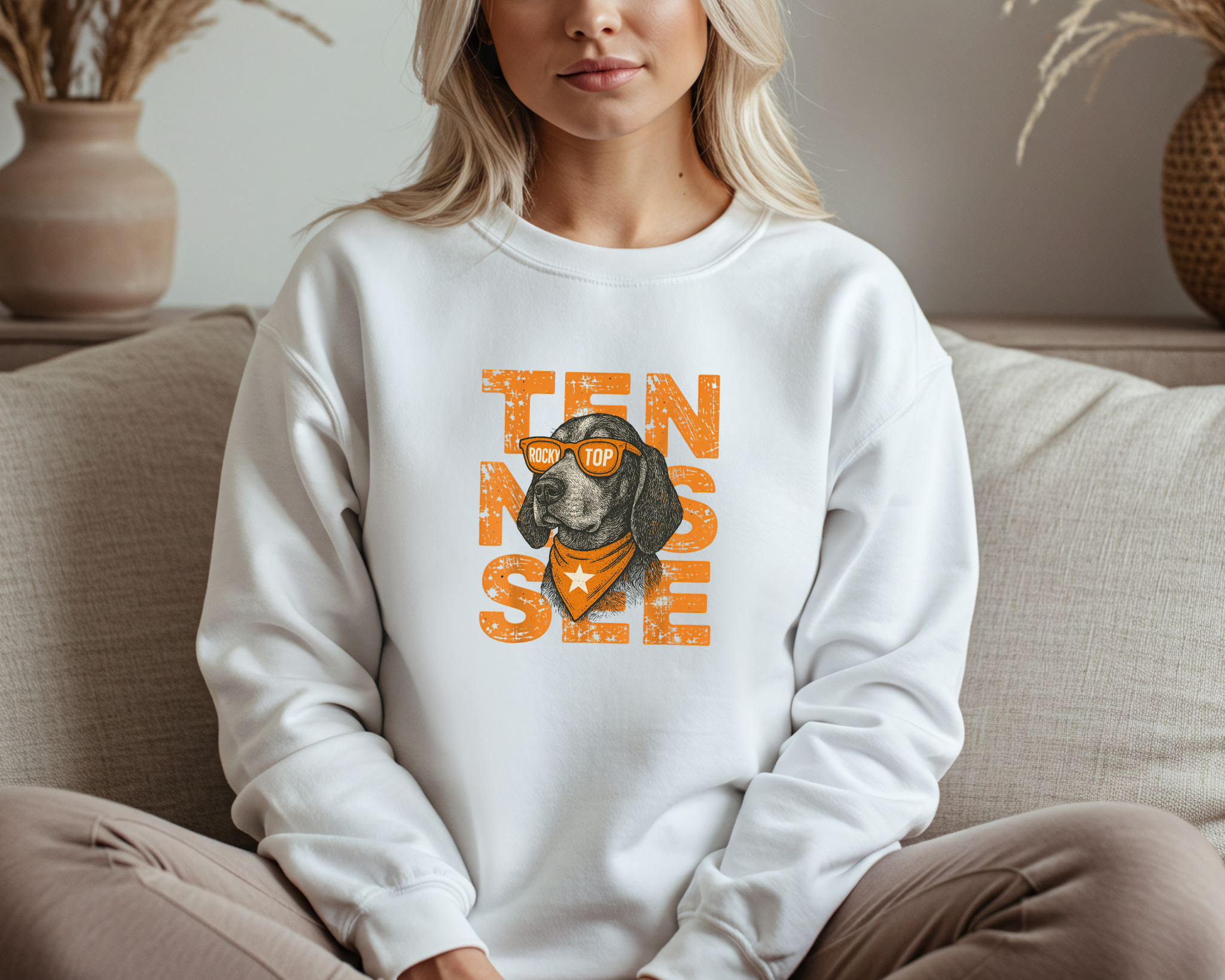 Person wearing a white sweatshirt with a dog graphic and 'TENNESSEE' text, sitting on a couch.
