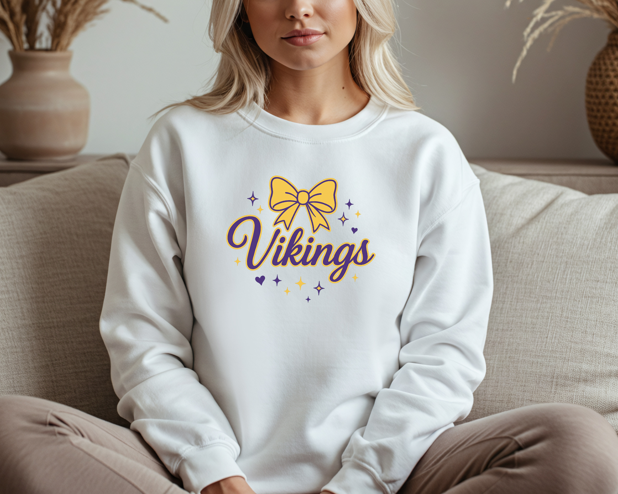 Person wearing a white sweatshirt with 'Vikings' and a yellow bow design.