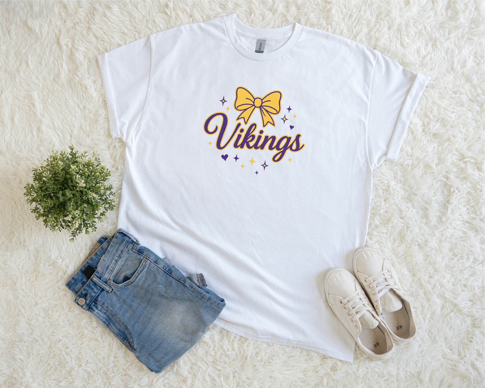 White t-shirt with 'Vikings' design, blue jeans, and white sneakers on a light background