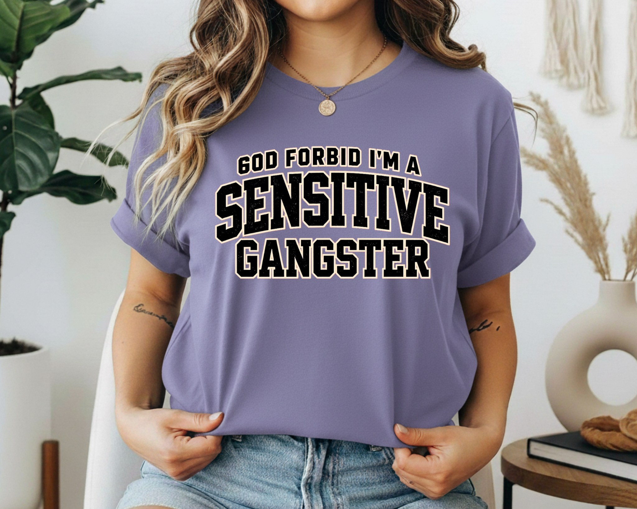 Person wearing a purple t-shirt with text 'GOD FORBID I'M A SENSITIVE GANGSTER' in a casual setting.